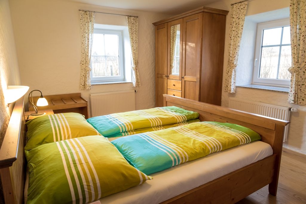 Gemütliches Schlafzimmer mit Holzmöbeln und bunten Bettbezügen.