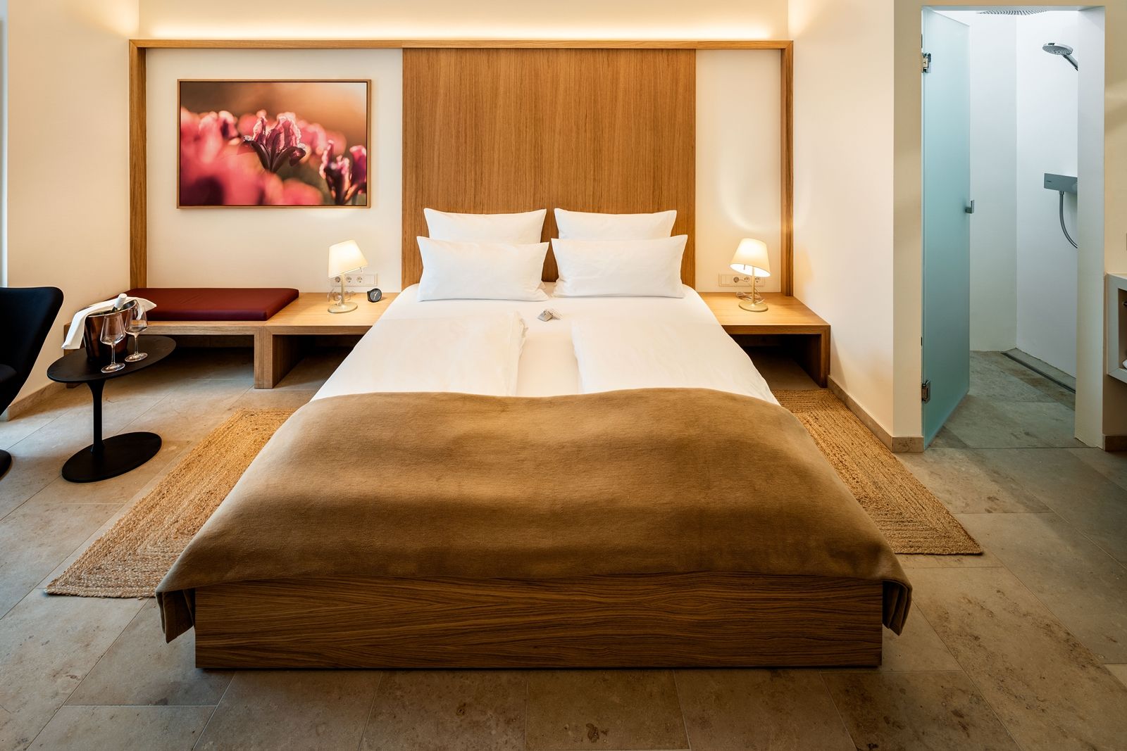 Modern eingerichtetes Hotelzimmer mit Doppelbett, Nachttischen, Lampen und einem Bild an der Wand.