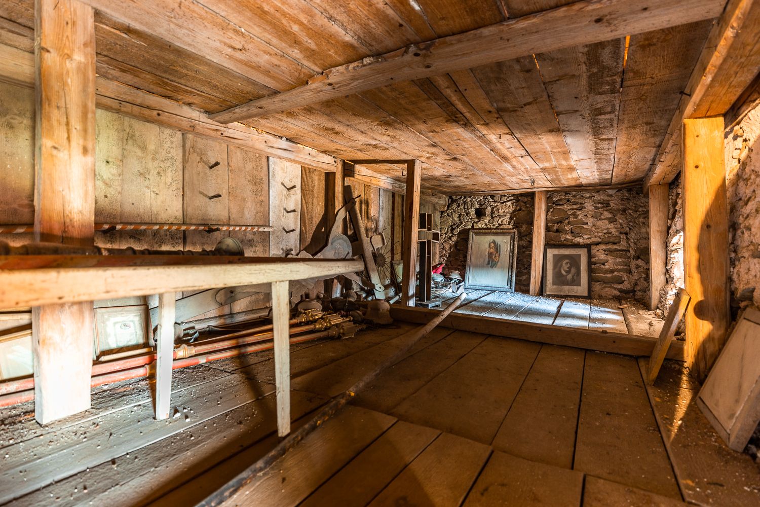 Innenansicht des Obergeschosses der Wehrkirche Lichtenegg mit Holzbalken und alten, verstaubten Bildern.