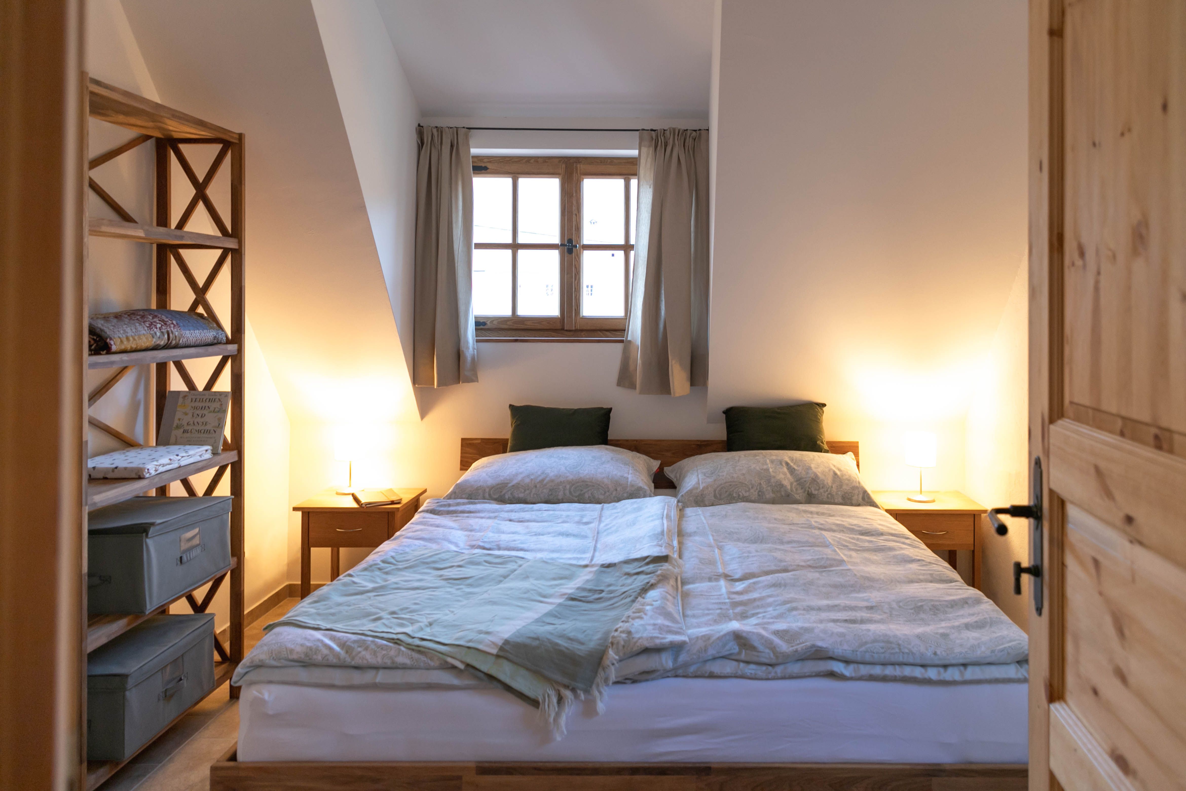 Gemütliches Schlafzimmer mit Doppelbett, Holzmöbeln und Fenster mit Vorhängen.