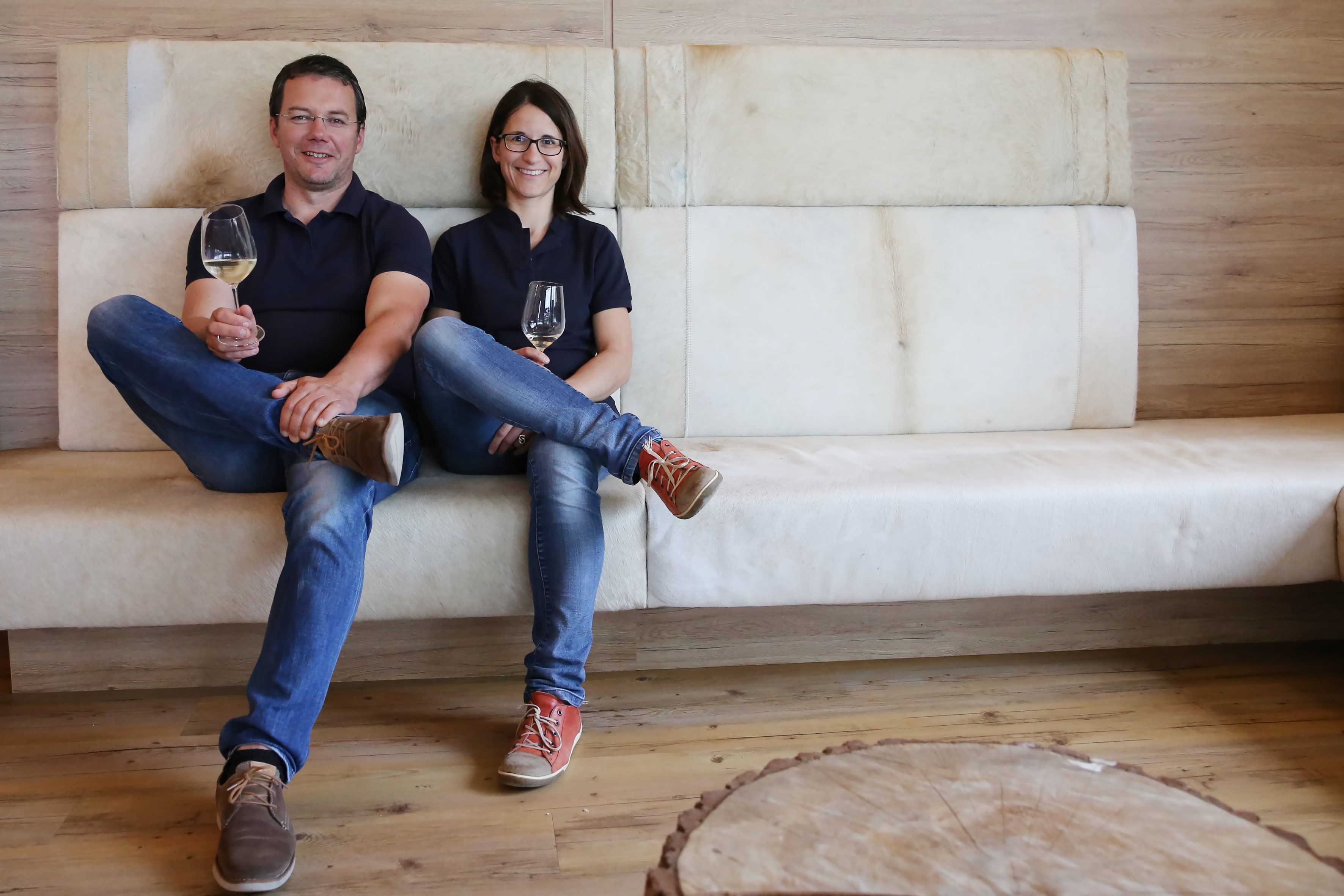 Ein Mann und eine Frau sitzen auf einem Sofa und halten Weingläser in der Hand.
