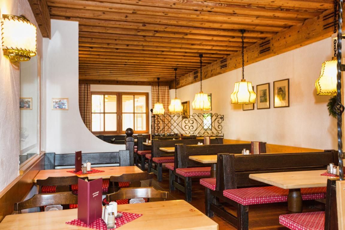 Gemütlicher Innenraum eines traditionellen Heurigen mit Holzmöbeln und karierten Sitzpolstern.