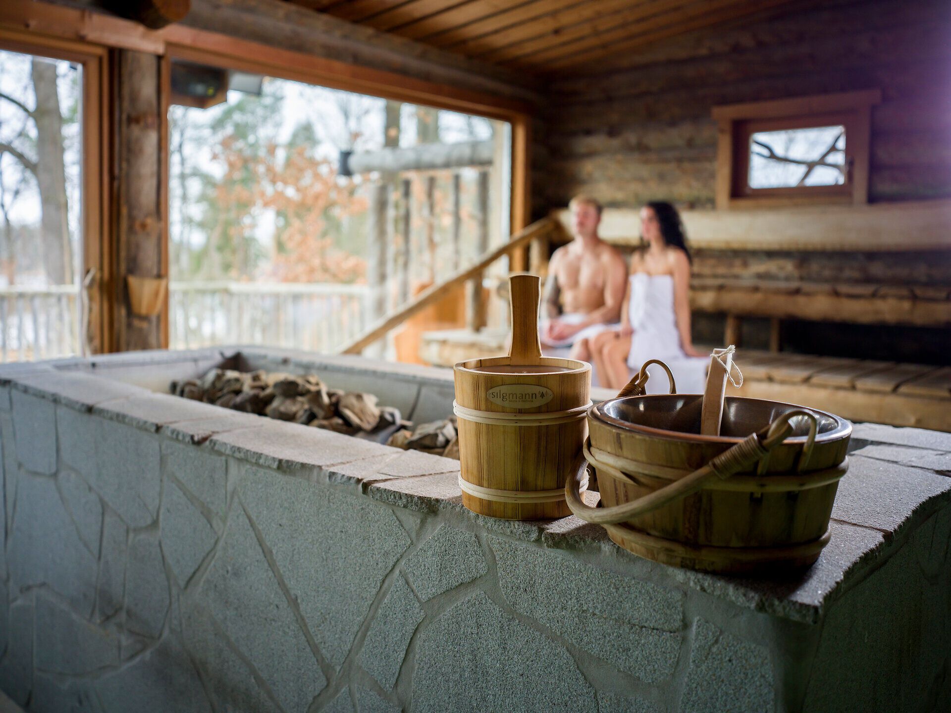 Modernes Hotelzimmer mit Doppelbett, Naturbild an der Wand, Sessel, Tisch und Stehlampe.