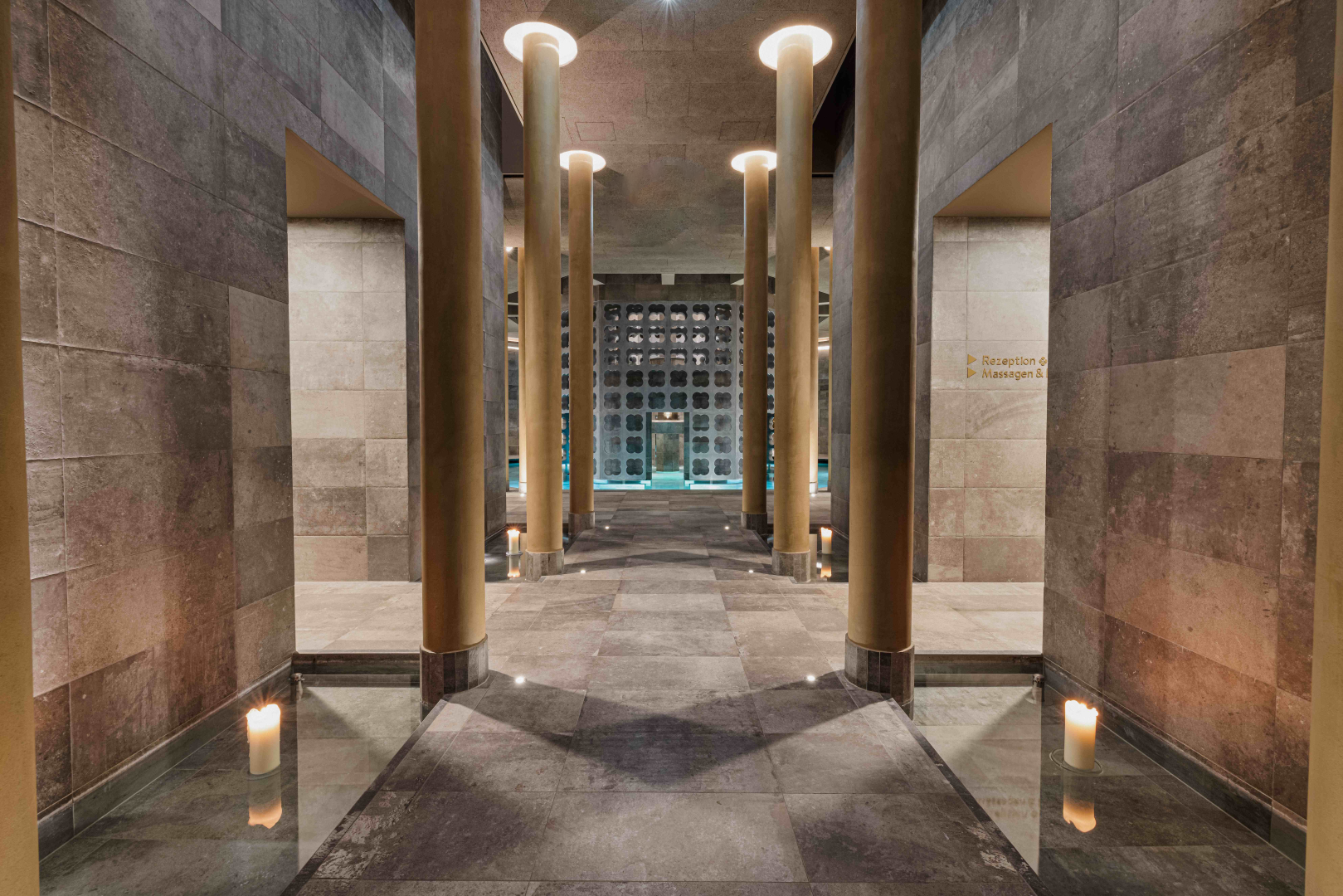 Innenansicht eines eleganten Spa-Bereichs mit Säulen und Kerzen.
