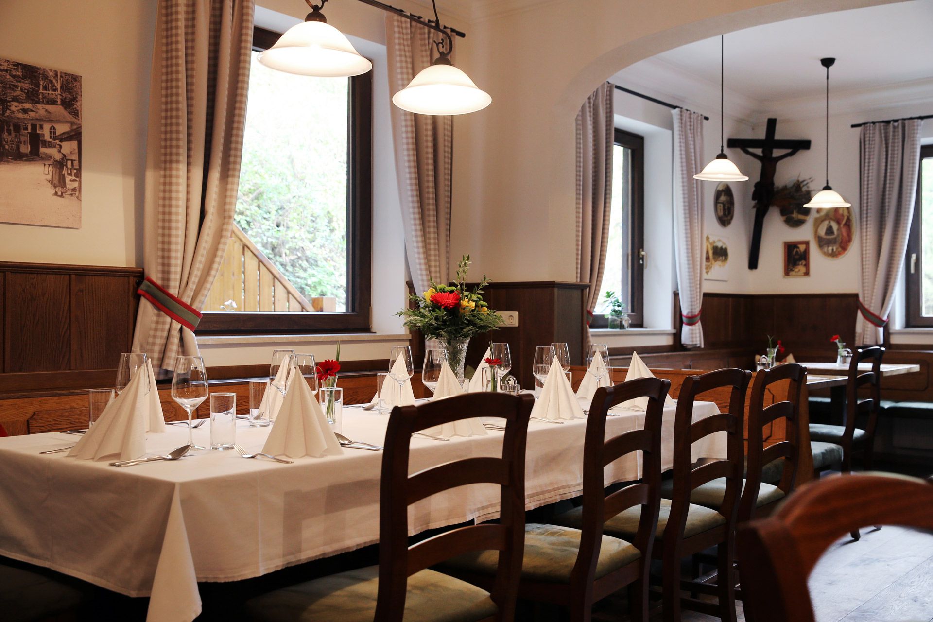 Innenraum eines gemütlichen Gasthofs mit gedecktem Tisch, Holzmöbeln und Dekorationen an den Wänden.