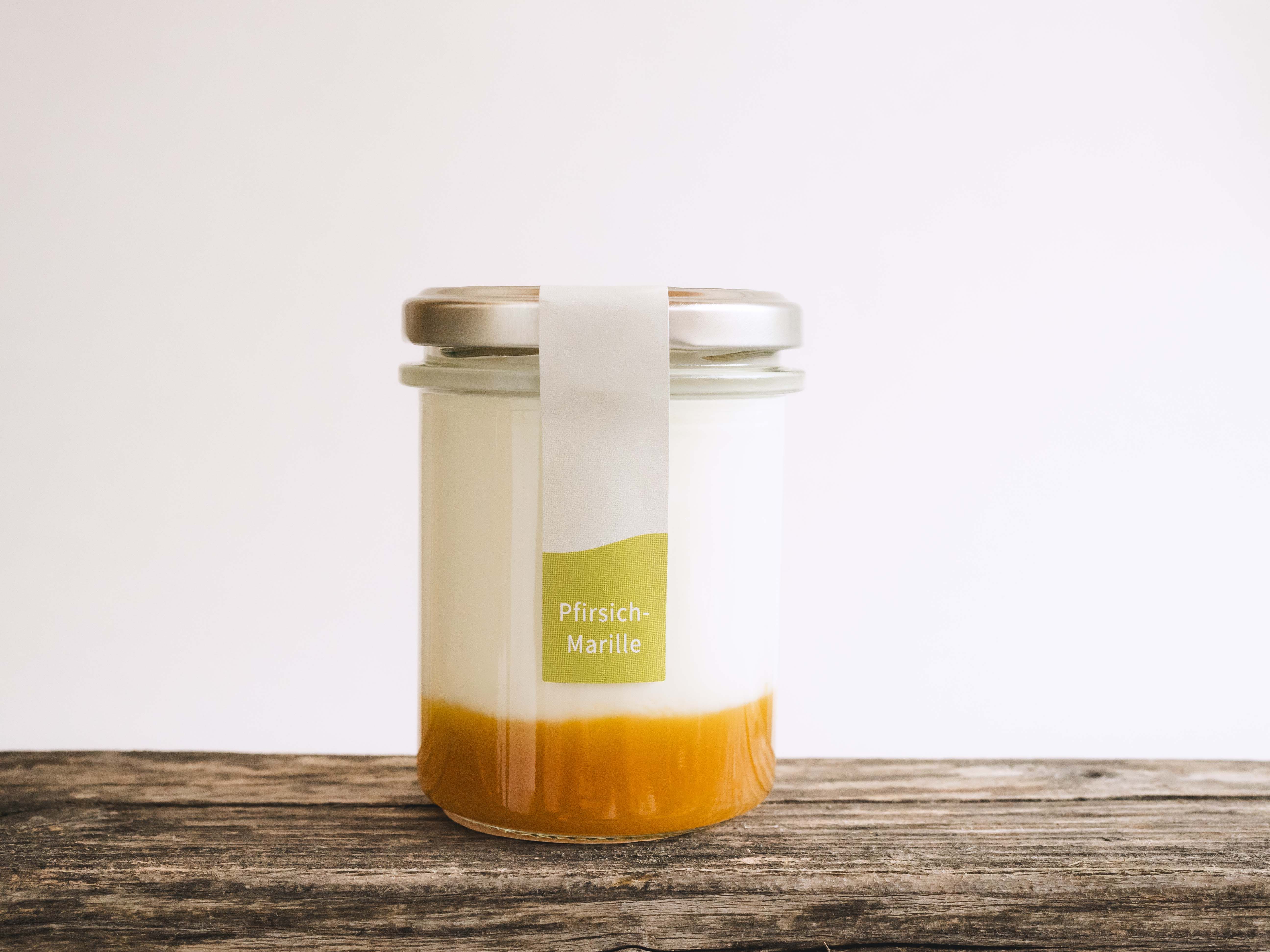 Ein Glas gefüllt mit Naturjoghurt und Fruchtspiegel auf einem Holztisch.