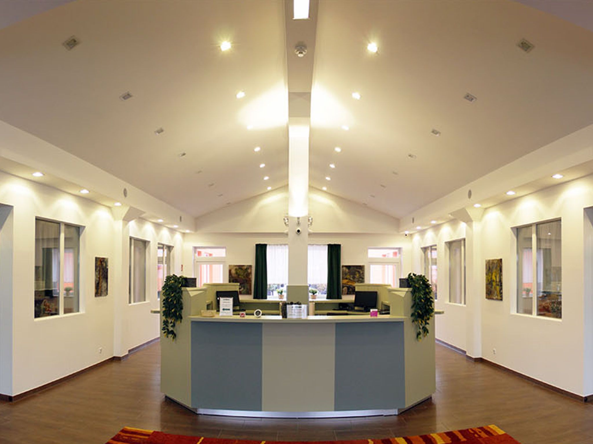 Modernes Empfangsbüro mit Schreibtisch und Pflanzen.