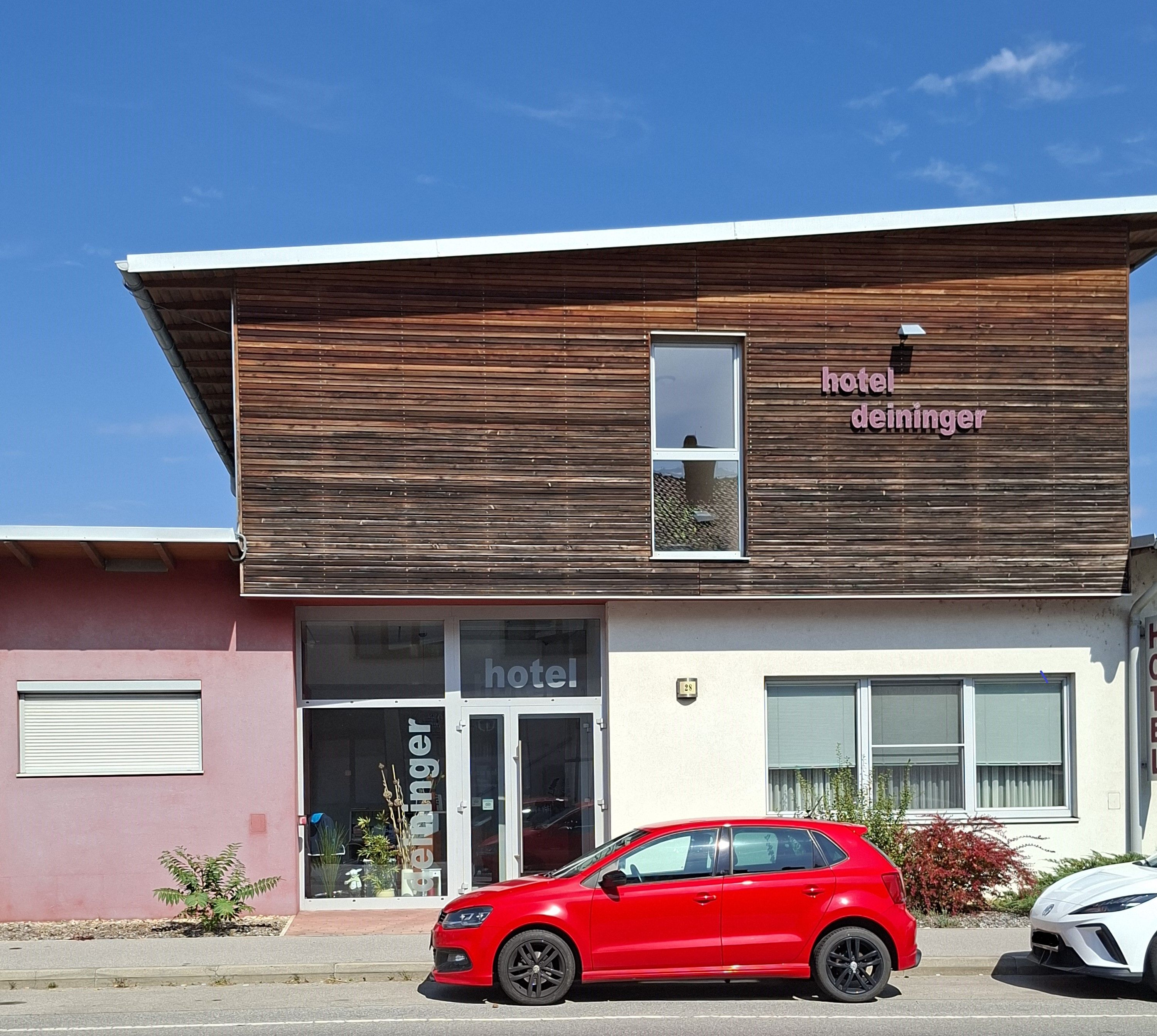 Fassade des Hotel Deininger mit rotem Auto davor.