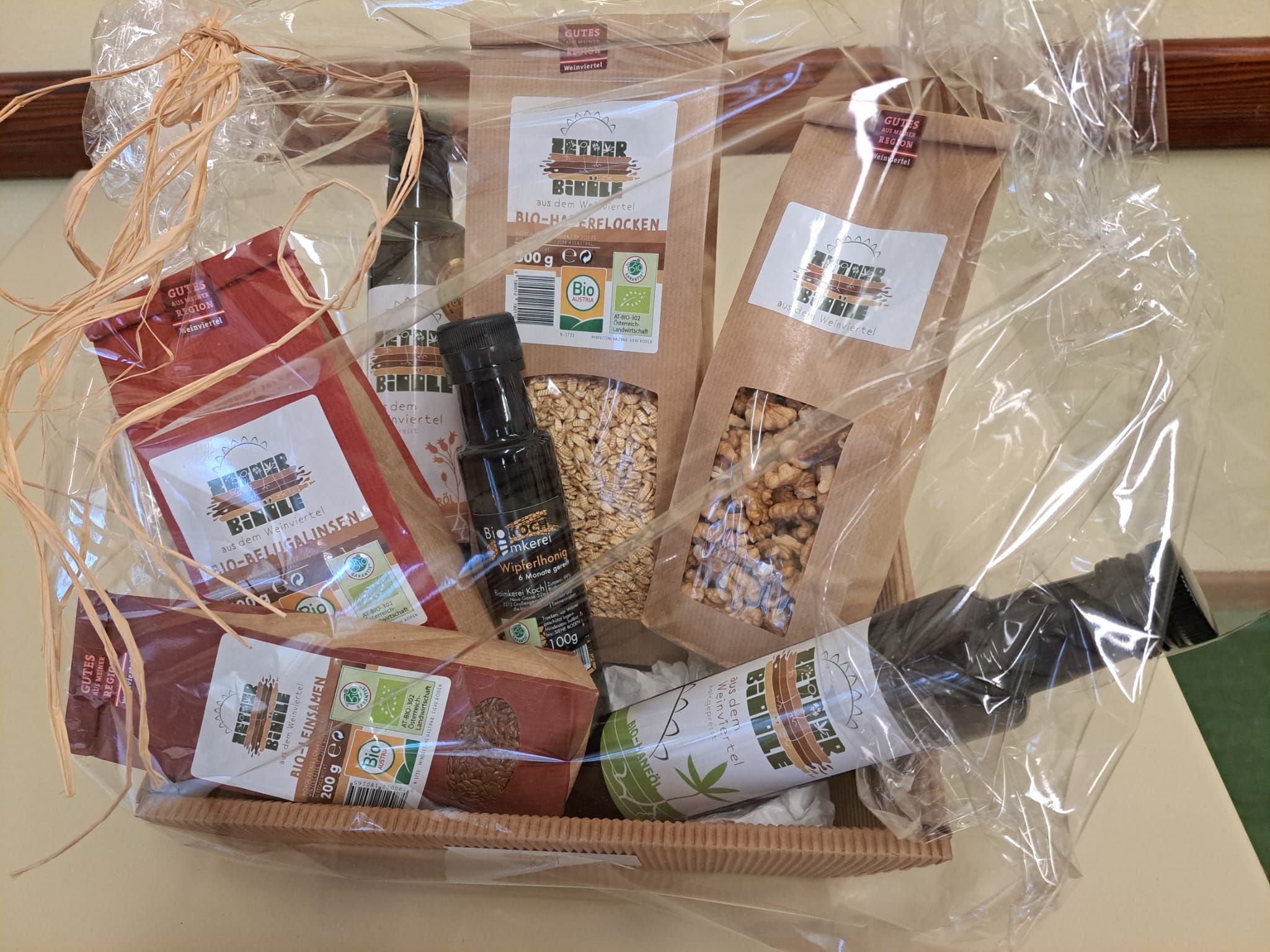 Geschenkkorb mit Bio-Produkten wie Öl, Honig und Getreideflocken.