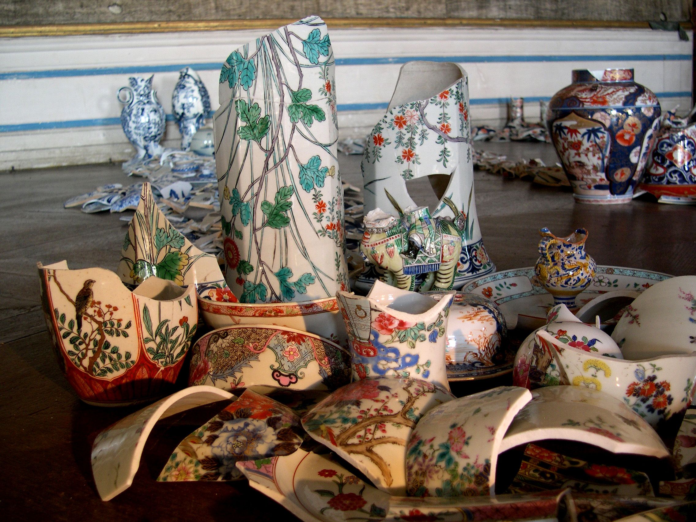 Zerbrochene Porzellanstücke mit bunten Mustern auf einem Boden arrangiert.