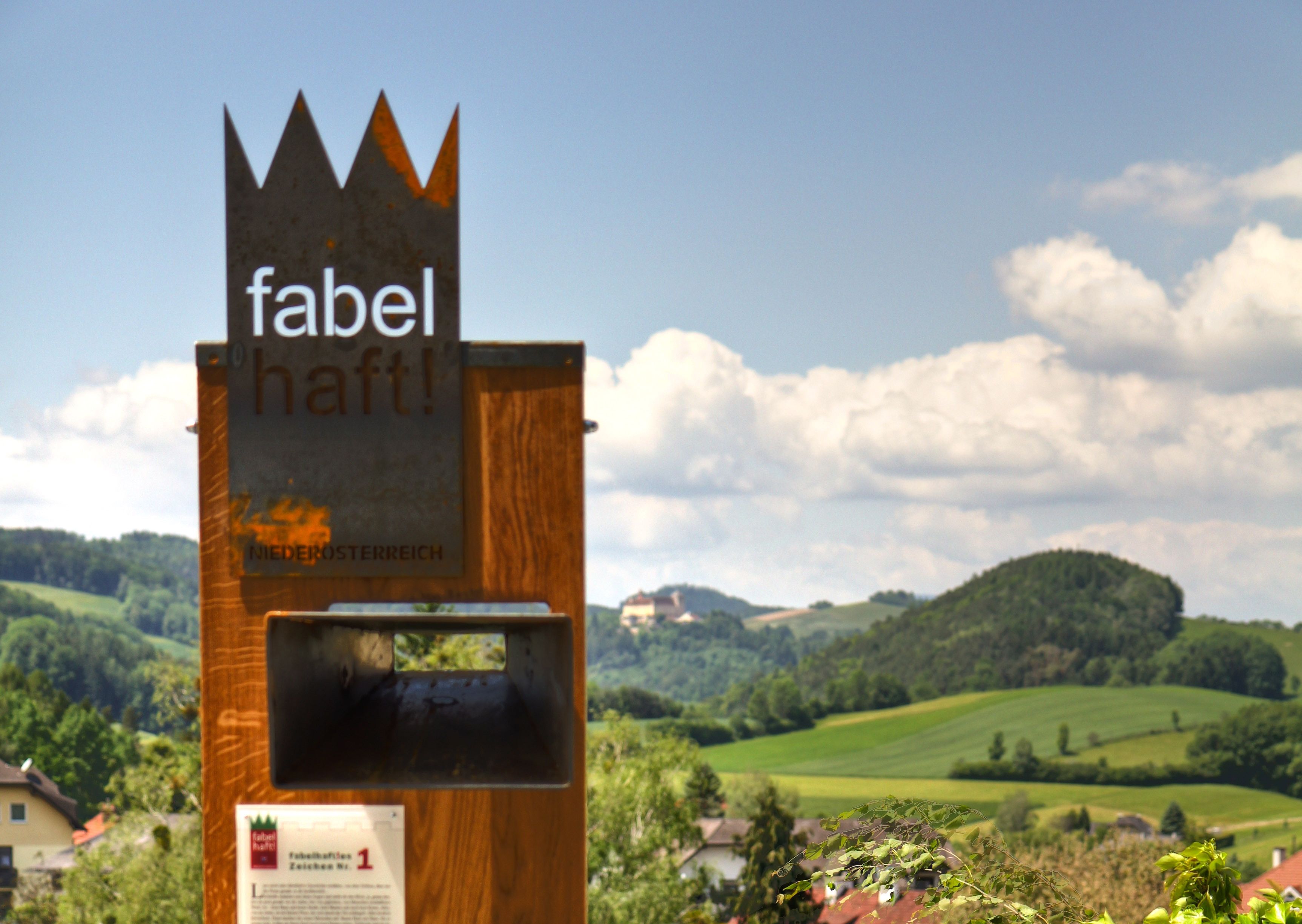 Metallskulptur mit der Aufschrift 'fabelhaft!' vor hügeliger Landschaft in Niederösterreich.