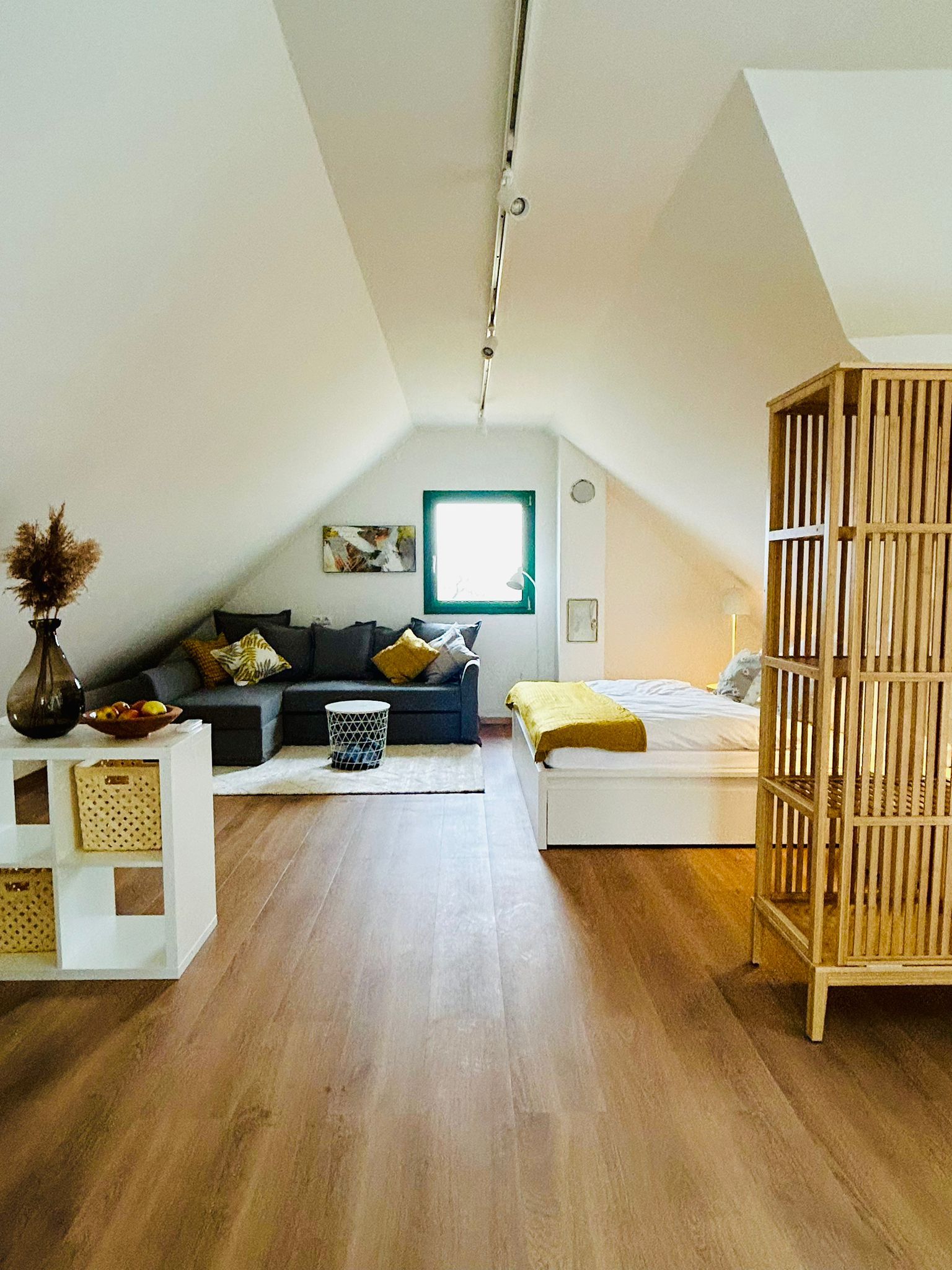 Gemütliches Dachgeschoss-Apartment mit Sofa, Bett und Holzboden.