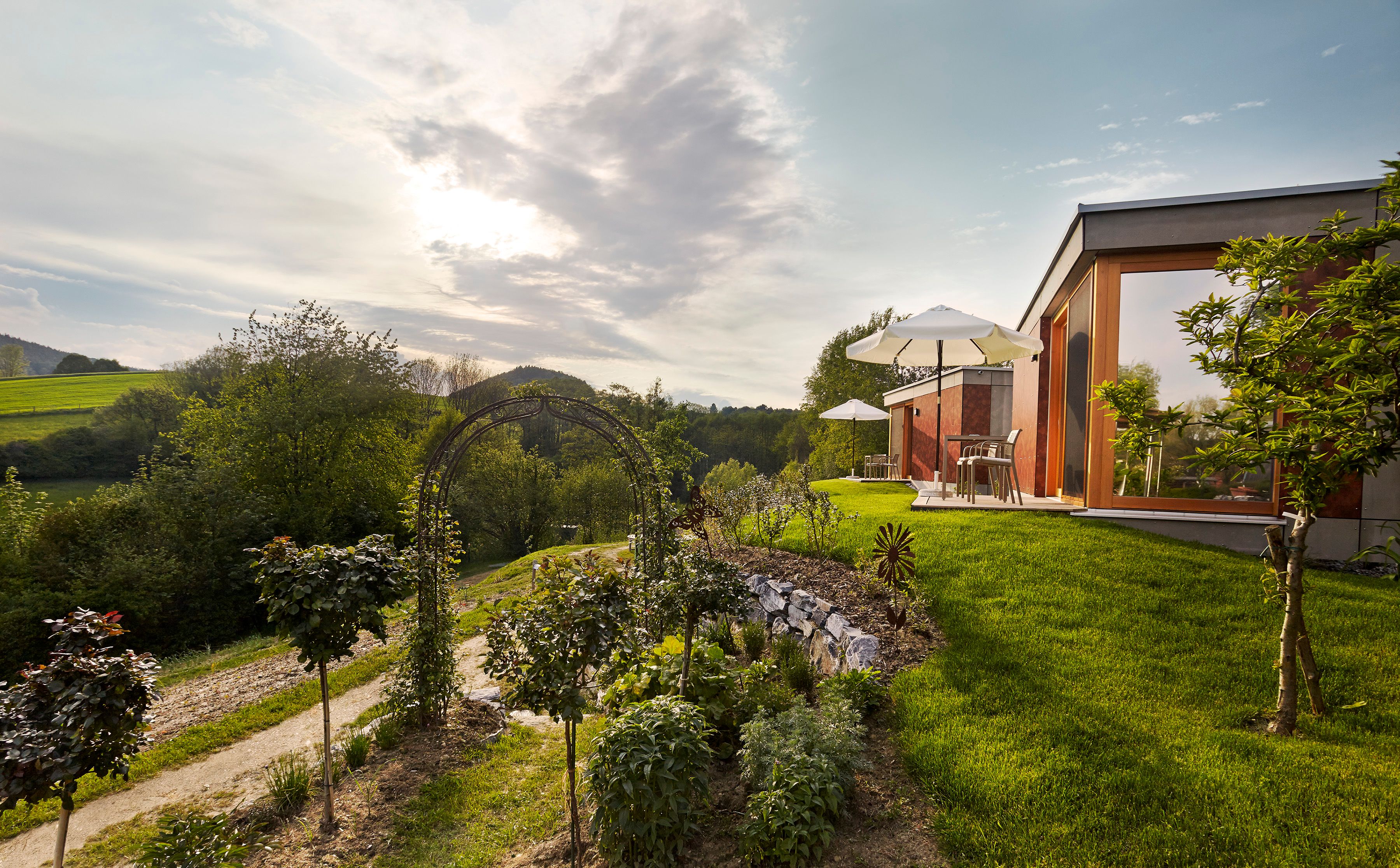 Moderne Unterkunft in grüner Landschaft mit Sonnenschirmen und Garten.