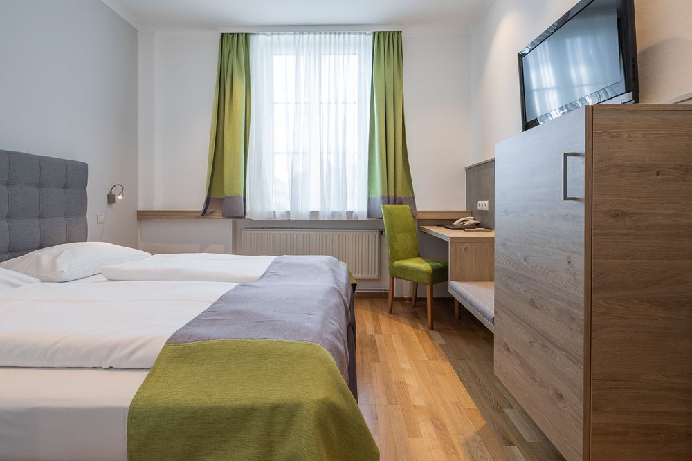 Modernes Hotelzimmer mit Doppelbett, Schreibtisch und Fernseher.
