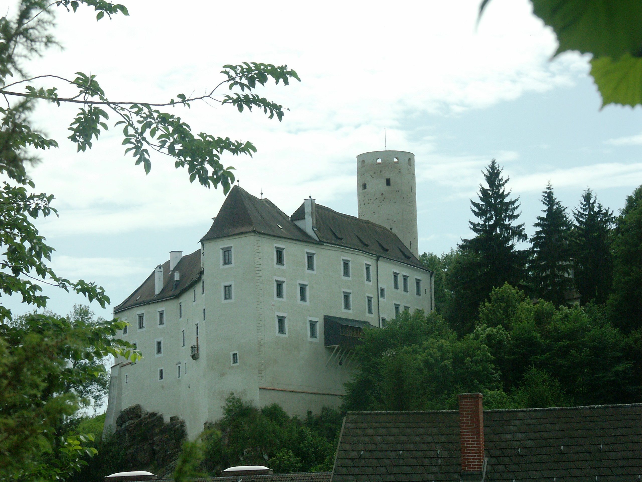 Burg Karlstein umgeben von Bäumen und einem blauen Himmel.