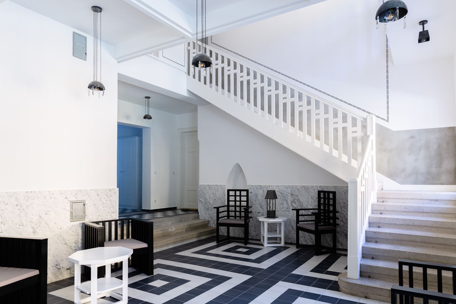 Moderner Eingangsbereich mit Treppe, schwarz-weißen Fliesen und minimalistischen Möbeln.