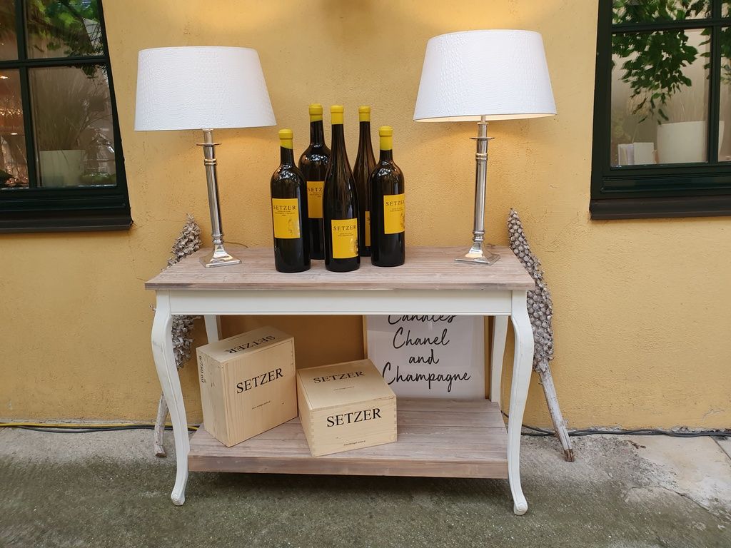 Konsolentisch mit Weinflaschen, Lampen und Holzkisten.