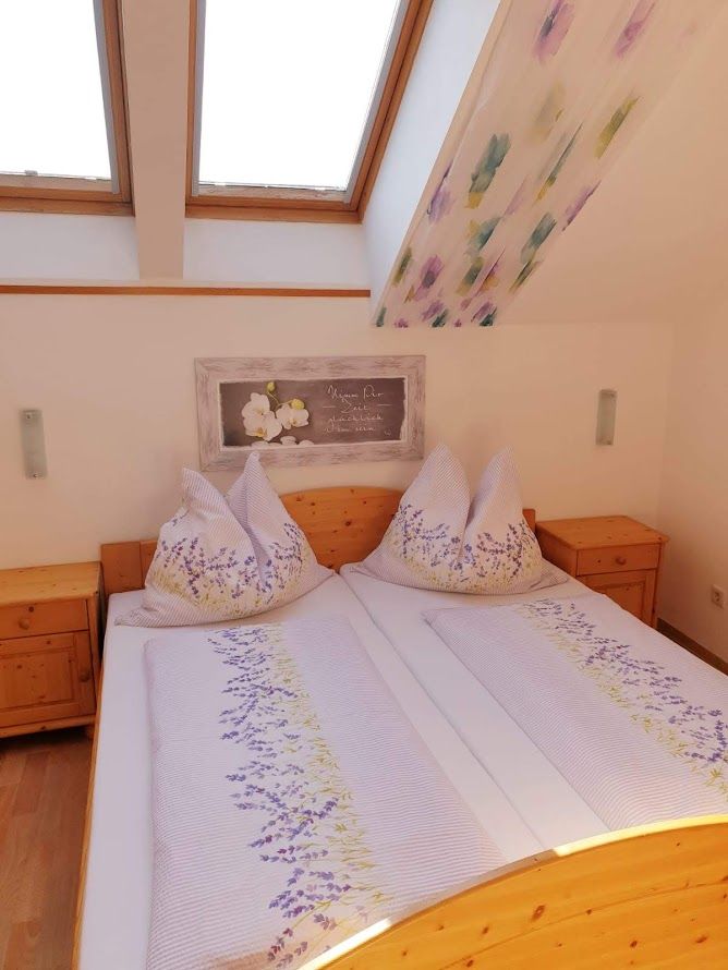 Gemütliches Schlafzimmer mit Dachfenstern und Blumenbettwäsche.