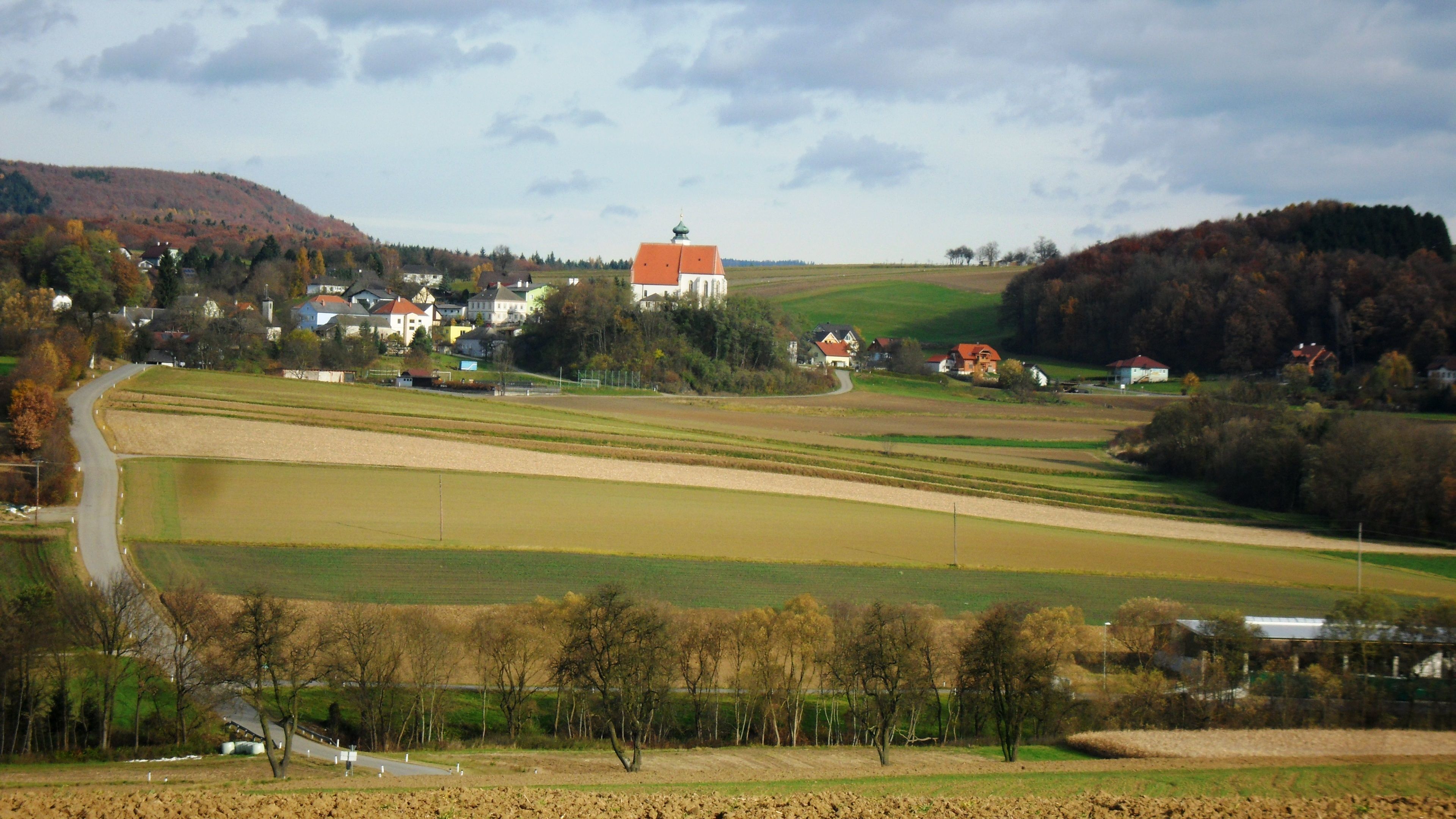 Landschaft mit Kirche und Feldern in Gerolding, Österreich.