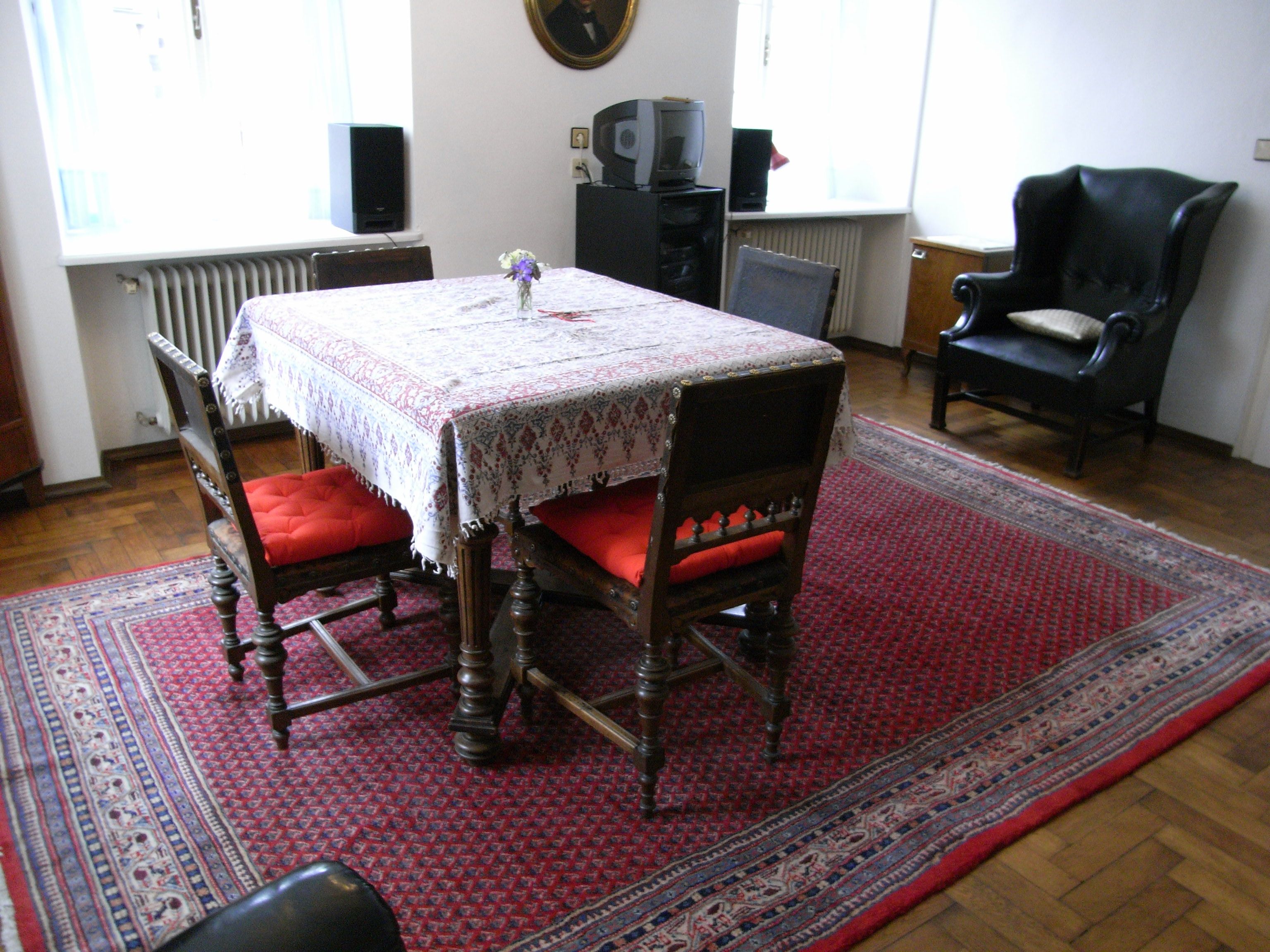 Wohnzimmer mit Tisch, Stühlen und Teppich.