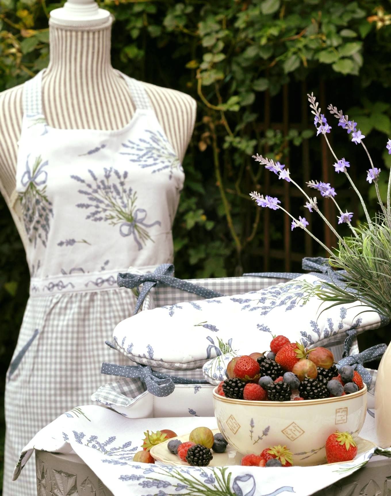 Eine Schale mit Beeren auf einem Tisch mit Lavendel-Dekoration und einer Schneiderpuppe mit Schürze im Hintergrund.