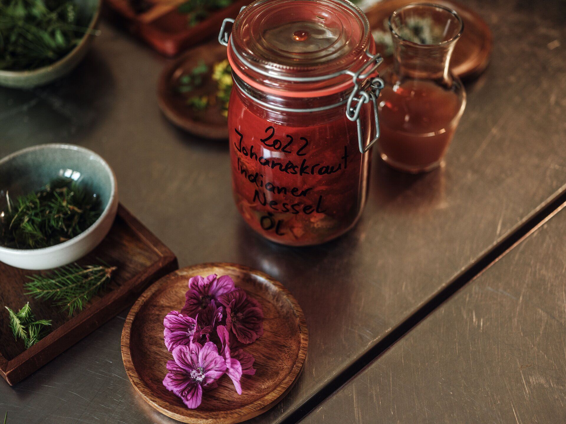 Ein liebevoll zubereitetes Glas mit aromatischem Nesselöl steht bereit, um die Sinne zu verzaubern. Umgeben von frischen Kräutern und bunten Blüten entfaltet sich hier die Kunst der Kulinarik inmitten der idyllischen Landschaft des Mostviertels. Ein Fest für die Augen und den Gaumen, das zum Entdecken und Genießen einlädt.