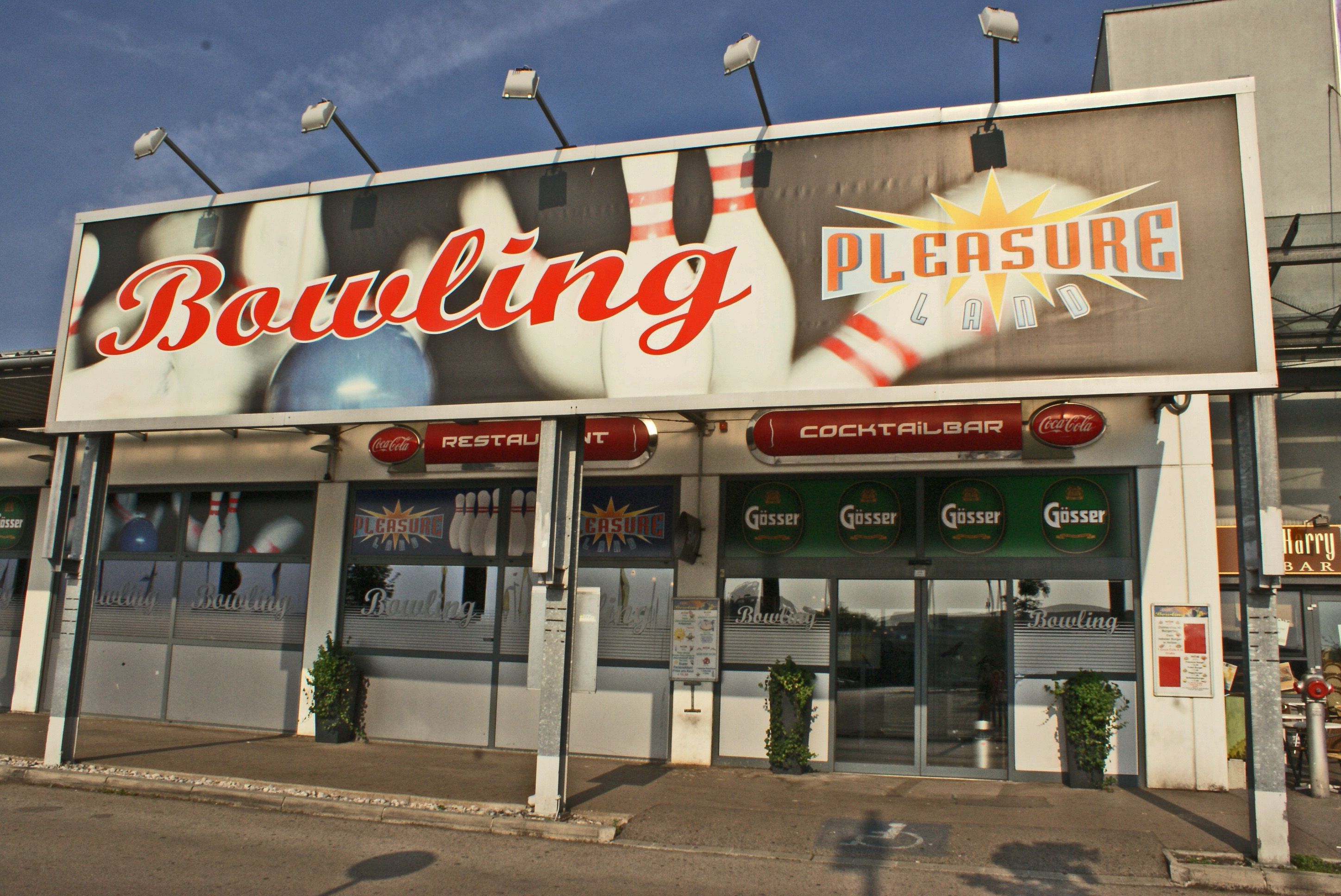 Eingang zu einem Bowlingcenter namens Pleasureland mit großen Schildern und Logos.