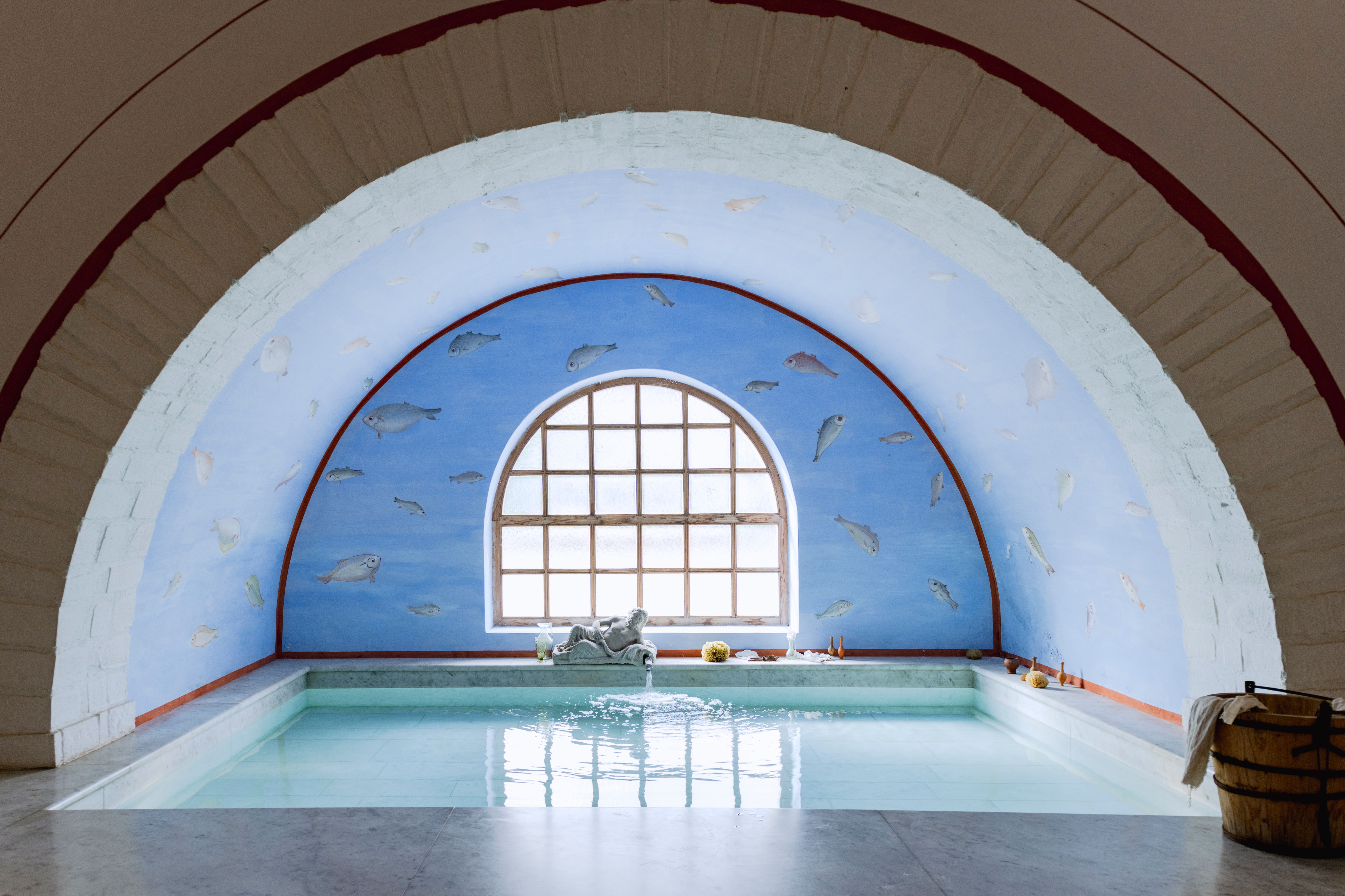 Römerstadt Carnuntum mit rekonstruierten Gebäuden und roten Dächern, umgeben von grünen Bäumen und Rasenflächen.