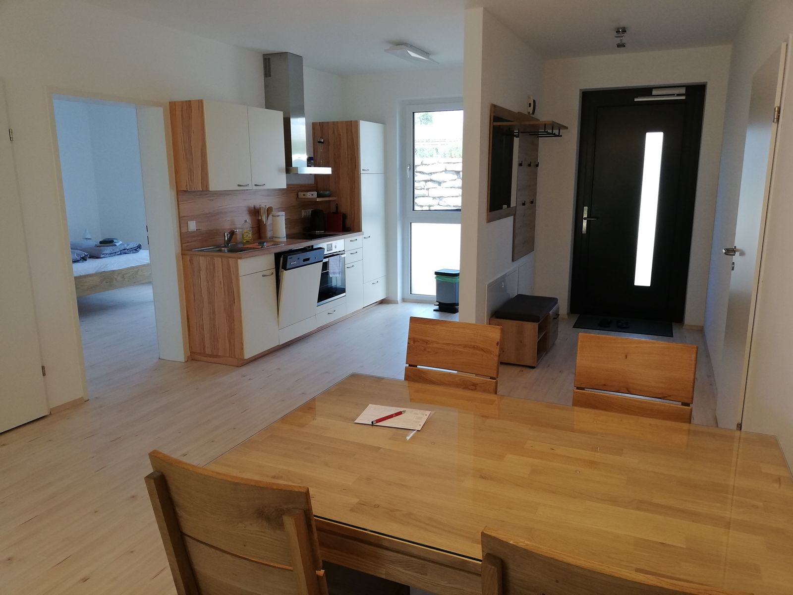 Moderne Wohnküche mit Holzmöbeln, Esstisch, Küchenzeile und Eingangstür.