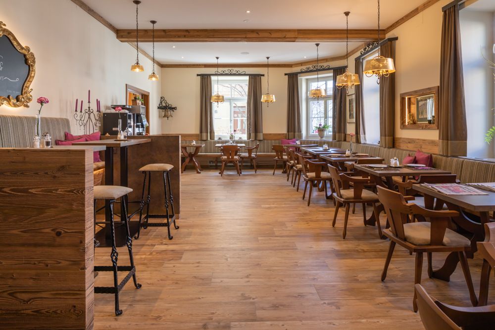 Gemütlicher Frühstücksbereich mit Holzmöbeln und großen Fenstern.