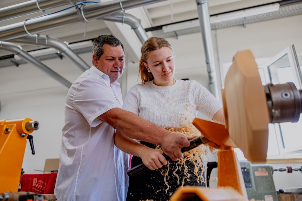 Ein Mann und eine Frau arbeiten gemeinsam an einer Drechselmaschine.