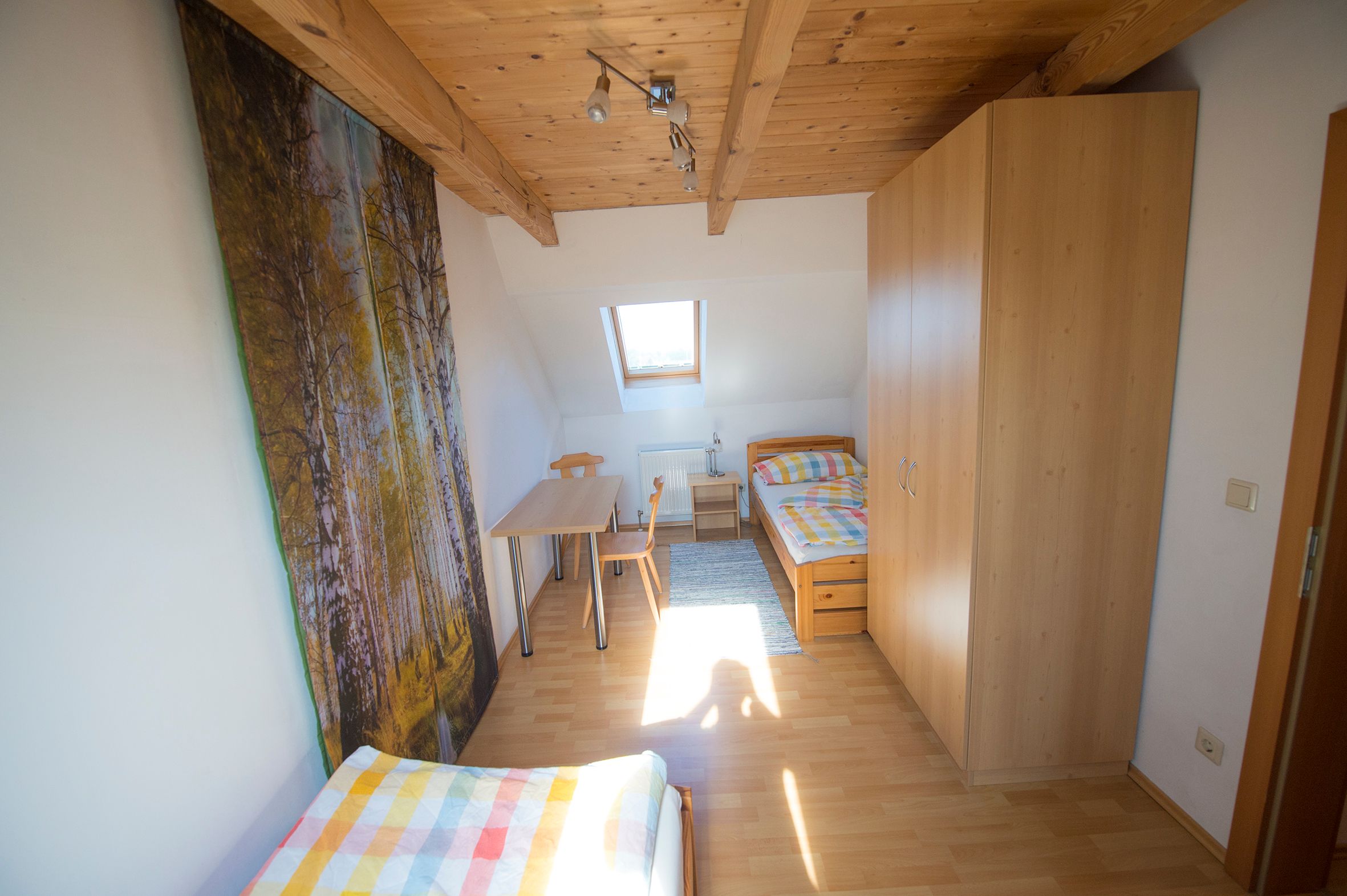 Großes Zimmer mit zwei Einzelbetten, kleinem Tisch, einem Fenster