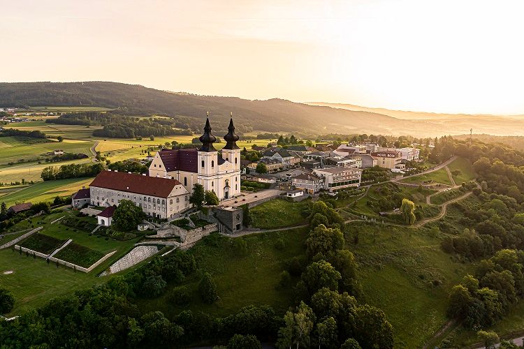Luftaufnahme von Maria Taferl mit Kirche und umliegender Landschaft bei Sonnenuntergang.