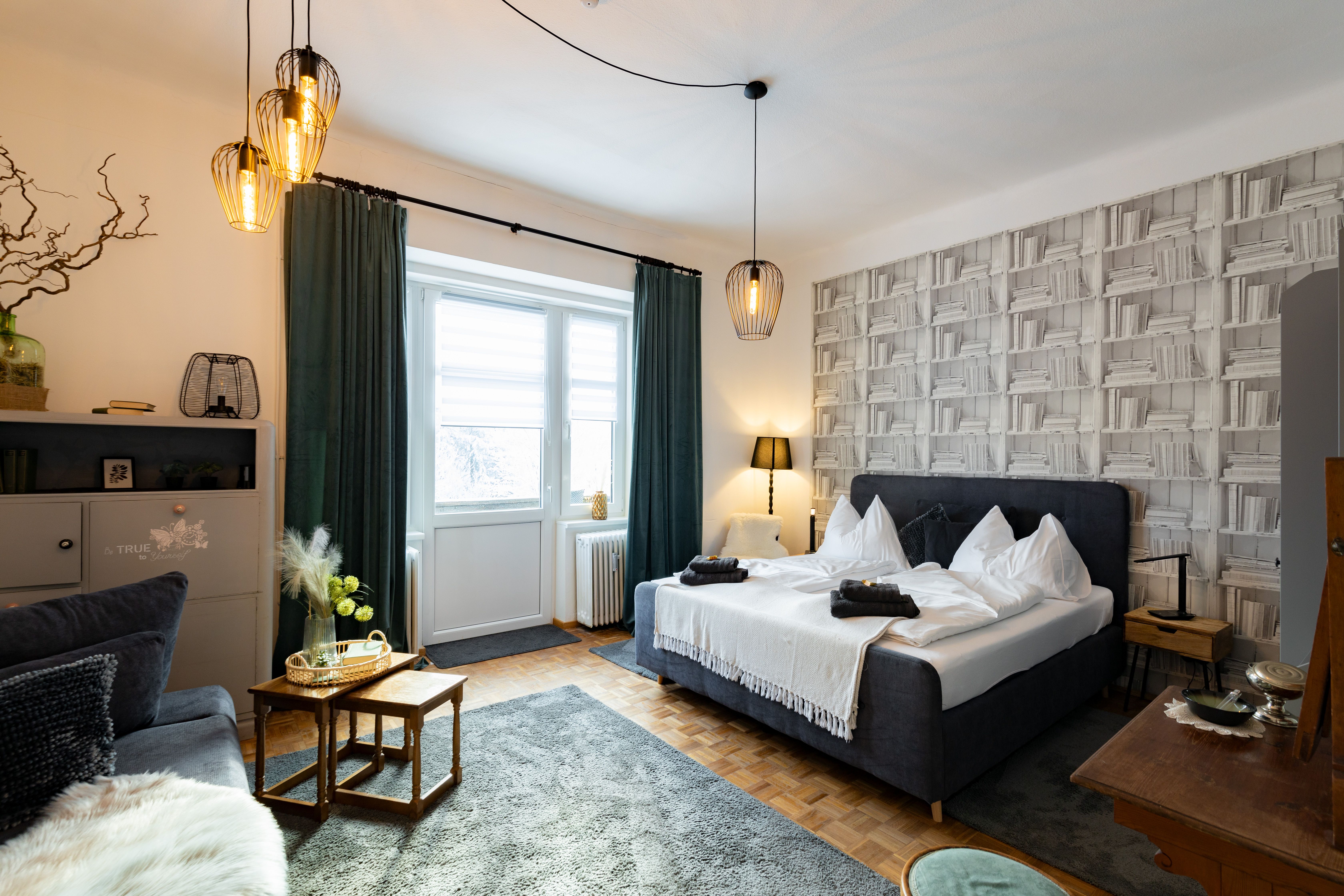 Gemütliches Schlafzimmer mit Doppelbett, dekorativen Lampen und Bücherregal-Tapete.