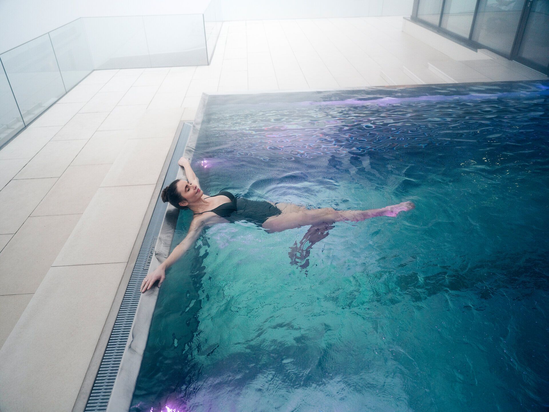 In einem eleganten Innenbereich lädt der glitzernde Pool zu entspannten Stunden ein. Die sanften Wellen des Wassers reflektieren das sanfte Licht und schaffen eine beruhigende Atmosphäre, die zum Verweilen einlädt.