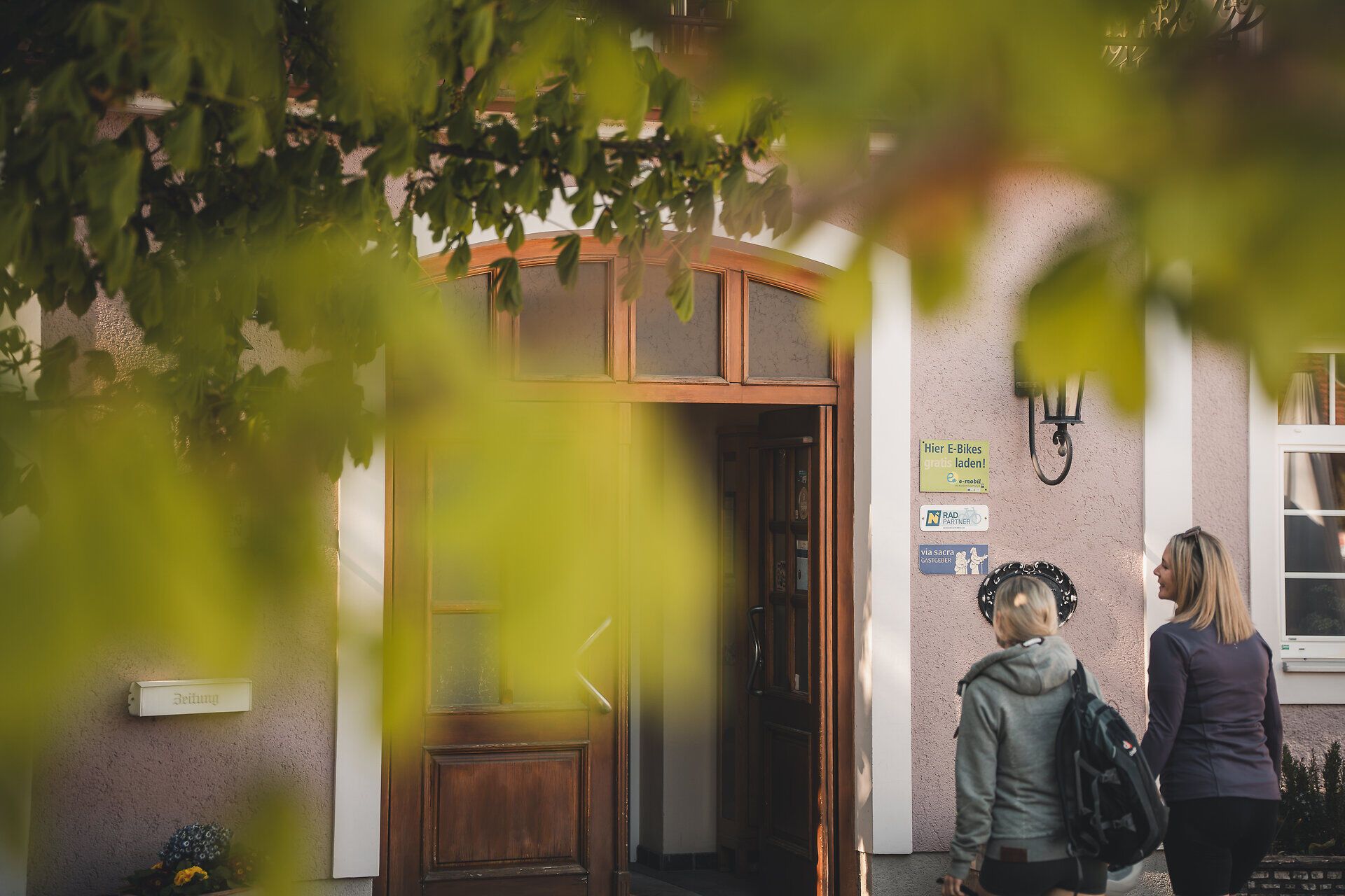 Zwei Frauen betreten ein Gasthaus.