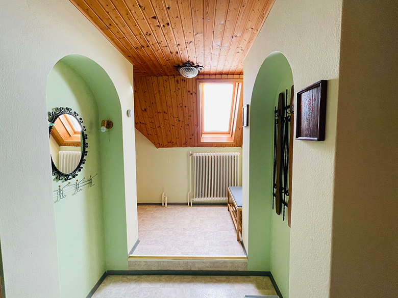Ein Vorraum mit Holzdecke, Dachfenster, Spiegel und Sitzbank.