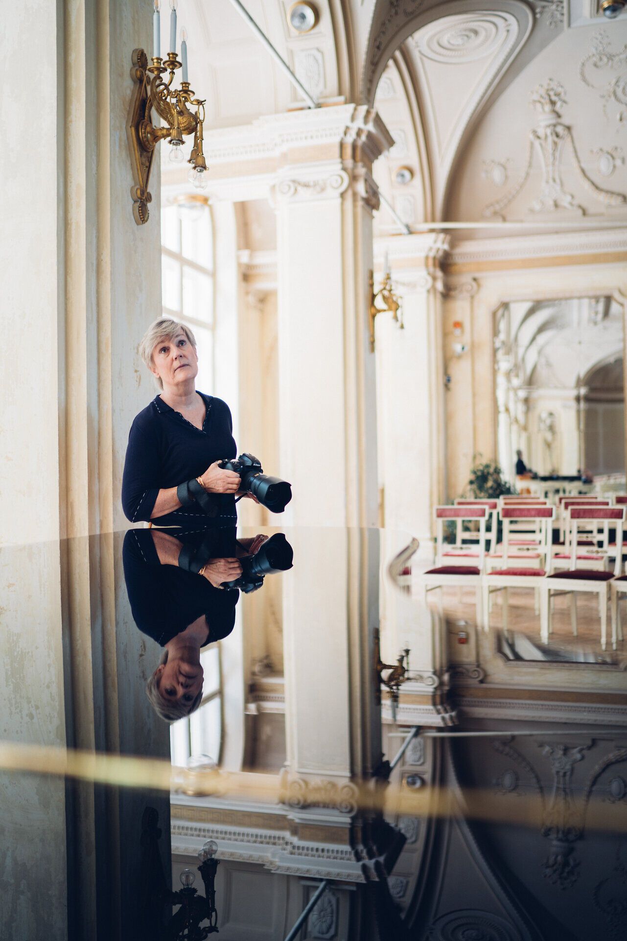 In der eleganten Atmosphäre des Südbahnhotels spiegelt sich die Schönheit der Umgebung in einem glänzenden Tisch. Die Fotografin Yvonne Oswald fängt den Moment ein, während sie die beeindruckende Architektur und die sanften Farben des Raumes bewundert.
