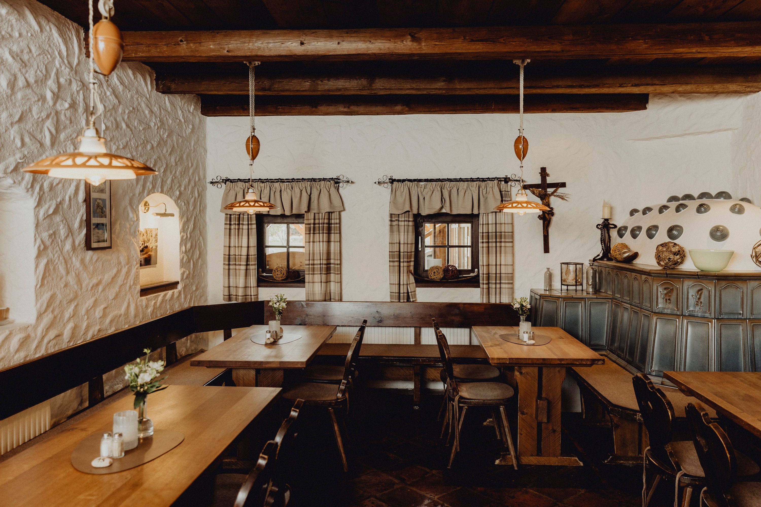 Gemütliche Stube mit Holzmöbeln, Kachelofen und rustikaler Dekoration.