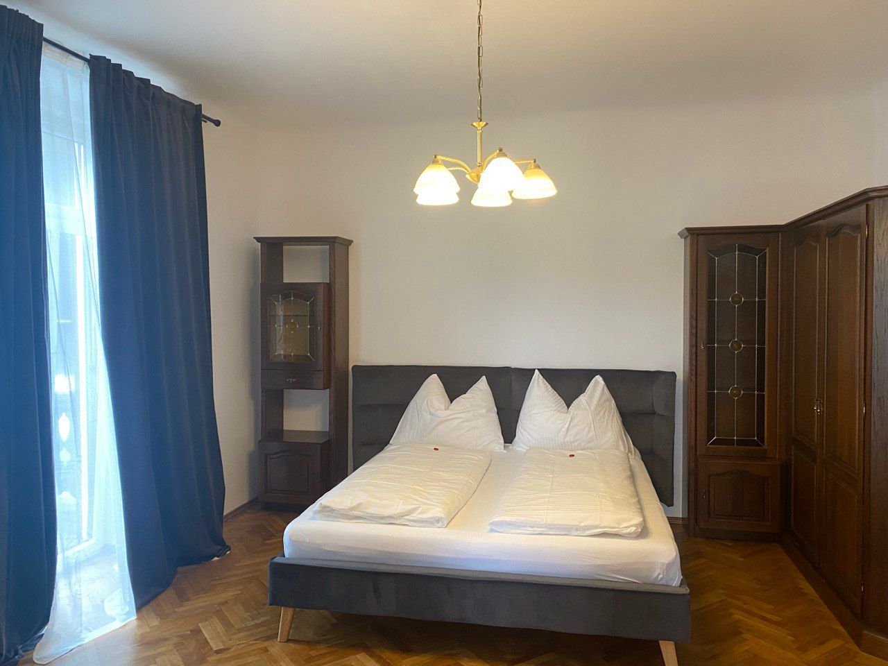 Schlafzimmer mit Doppelbett, dunklen Vorhängen und Holzschränken.