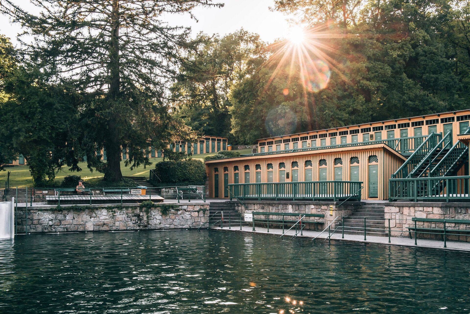 Unterwasseraufnahme eines Mädchens, das in einem klaren Naturbecken schwimmt.