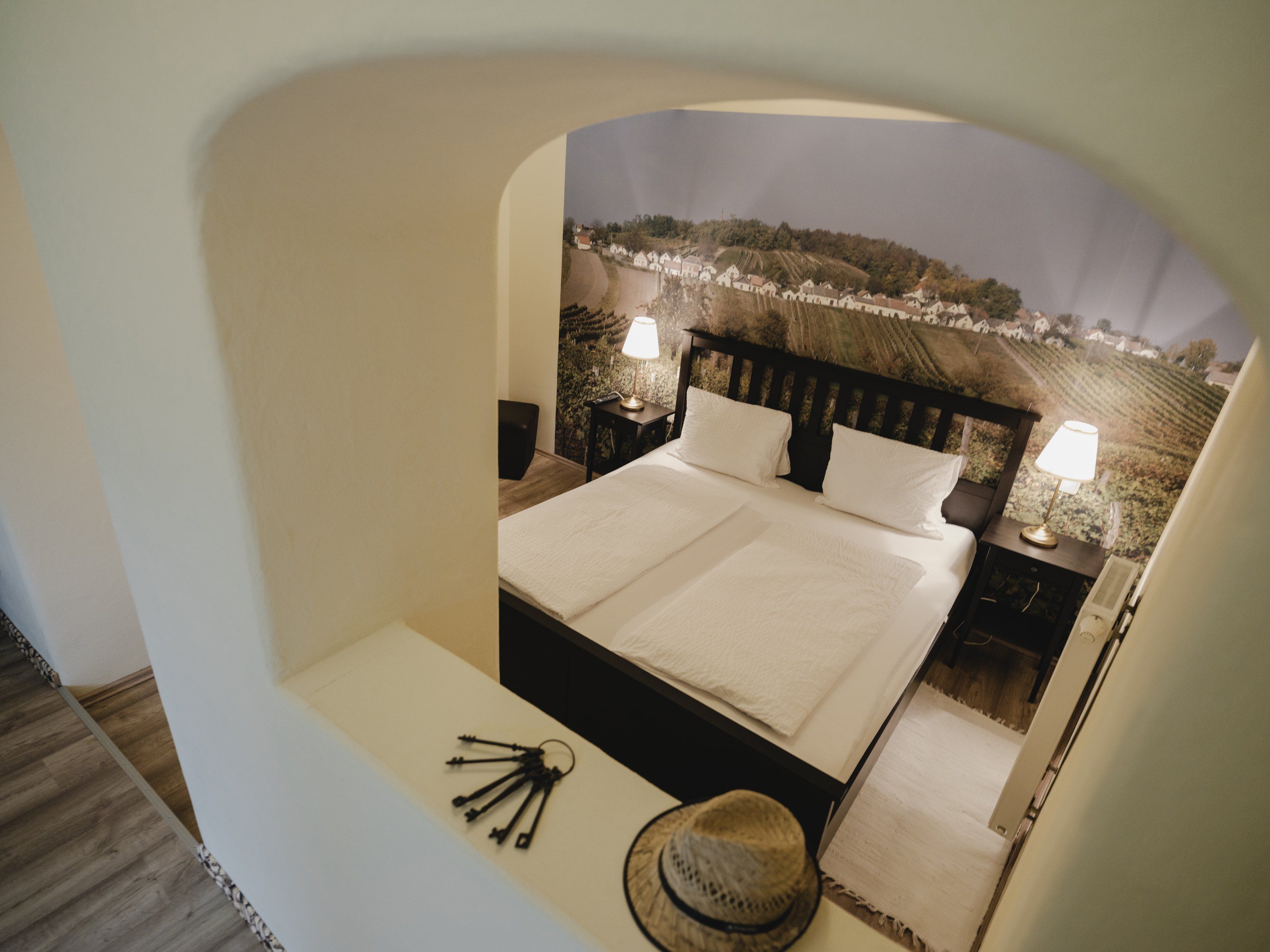 Gemütliches Schlafzimmer mit Doppelbett und Wandbild von Weinbergen.