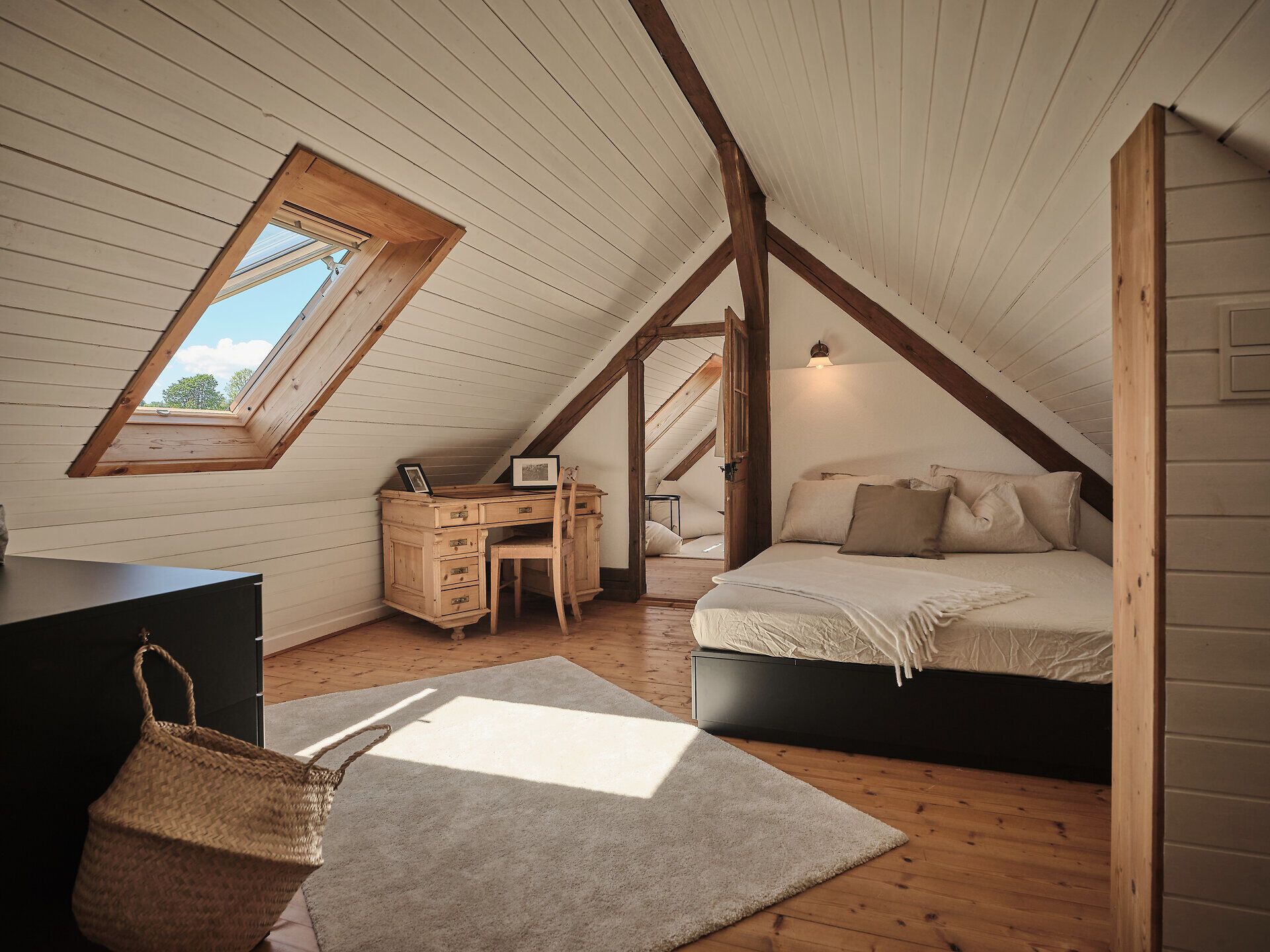 Rustikales Steinhaus mit Holztür, Bank und Blumen im Vordergrund.