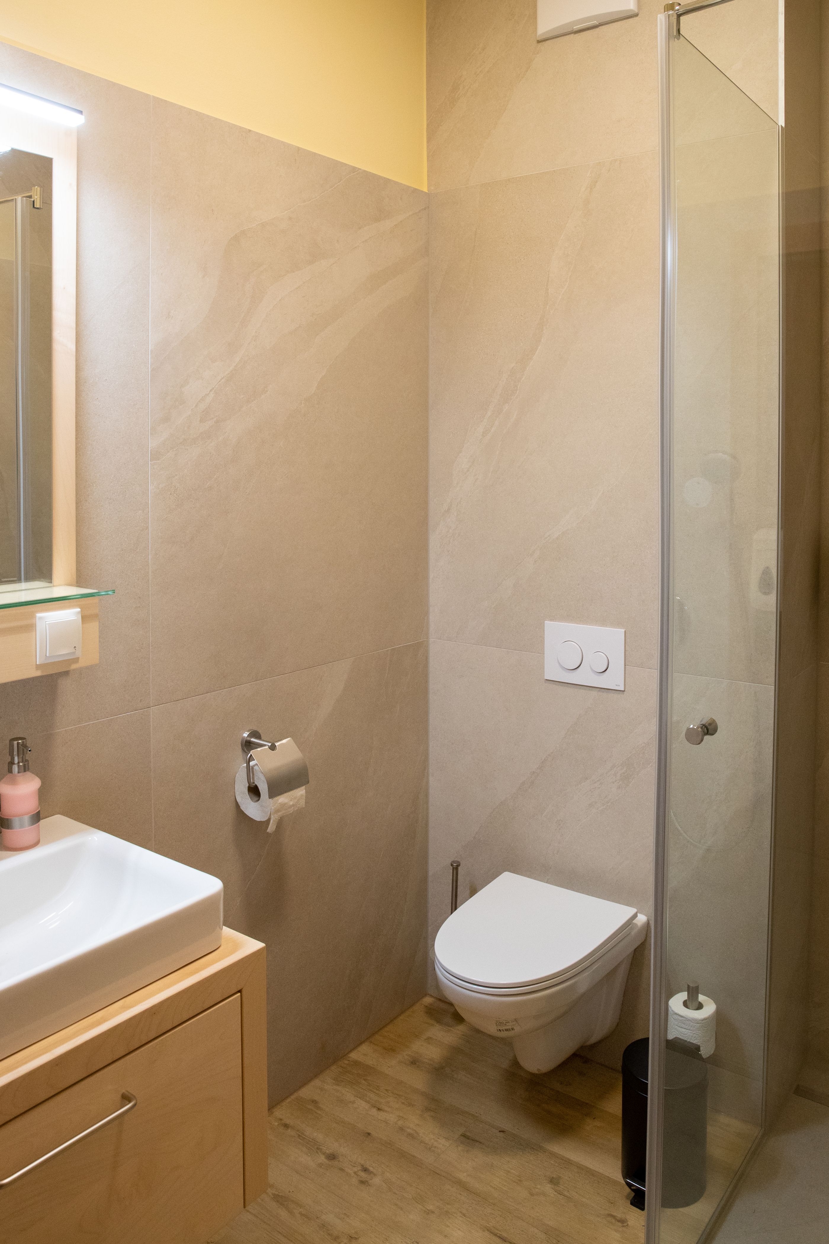 Modernes Badezimmer mit Waschbecken, Toilette und Duschkabine.