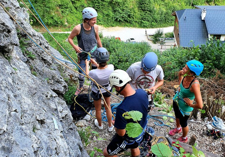 Gruppe von Menschen beim Klettern im Freien mit Helmen und Kletterausrüstung.