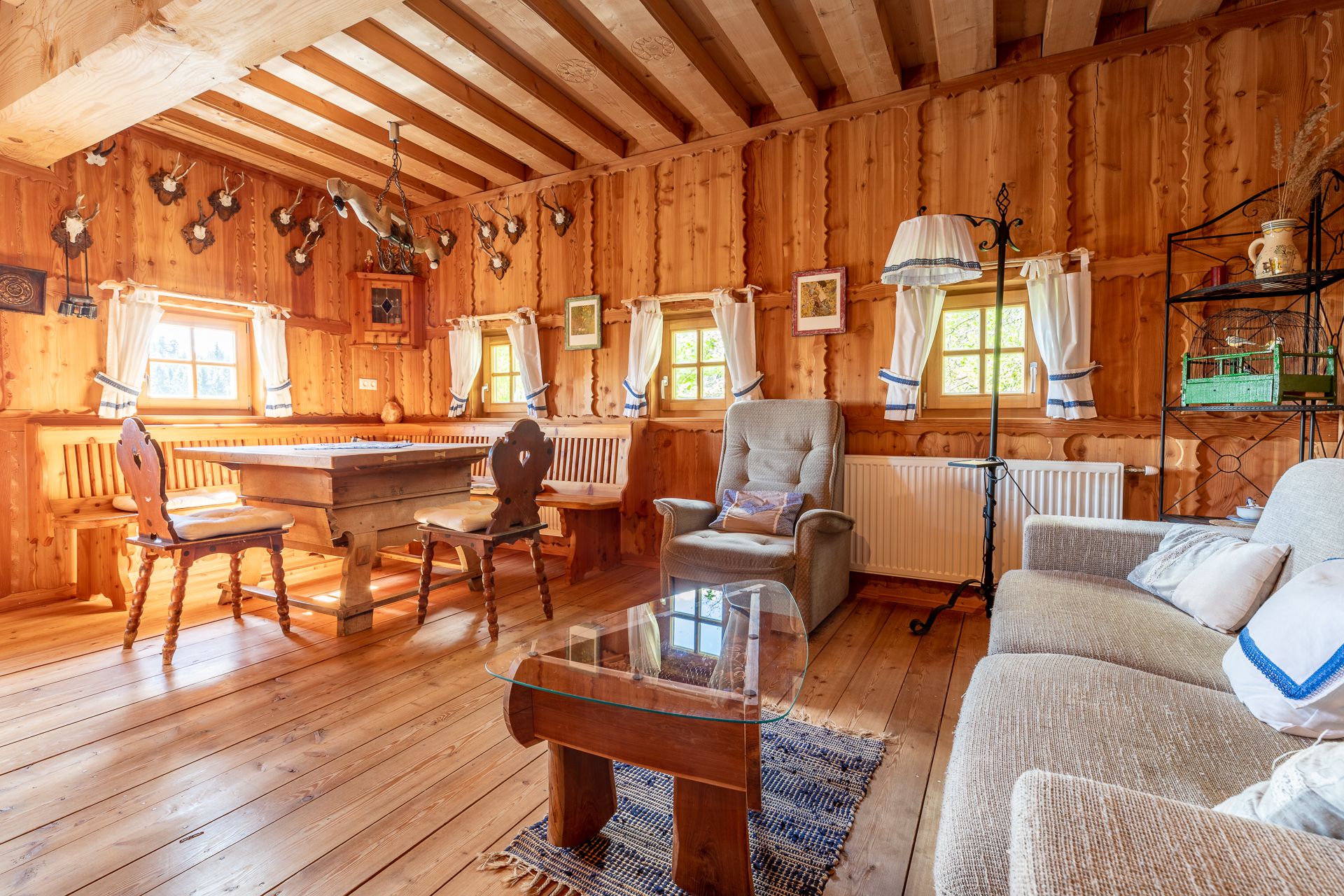 Rustikaler Wohn- und Essbereich mit Holzmöbeln, Holzwänden und Jagdtrophäen an der Wand.