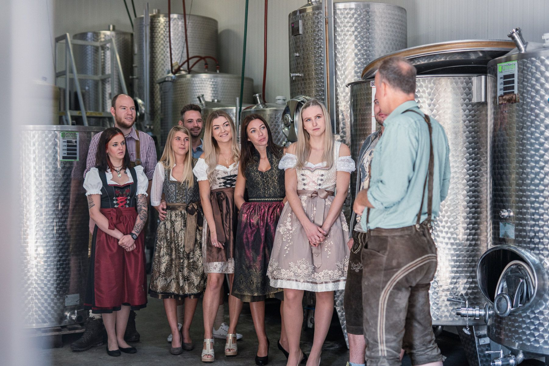 Gruppe von Menschen in traditioneller Kleidung in einer Brauerei.