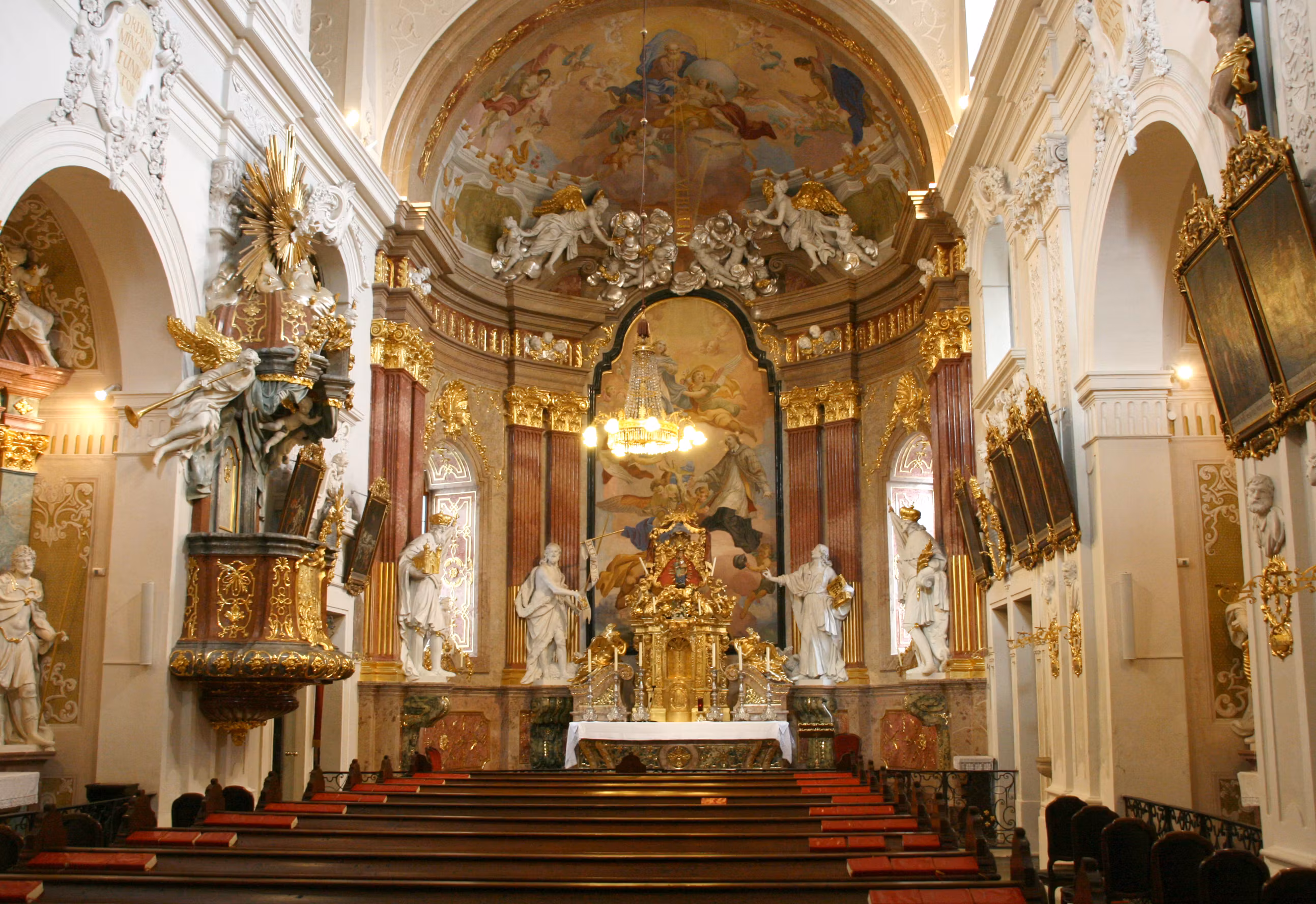 Innenansicht der Minoritenkirche mit reich verziertem Altar und Deckenfresken.