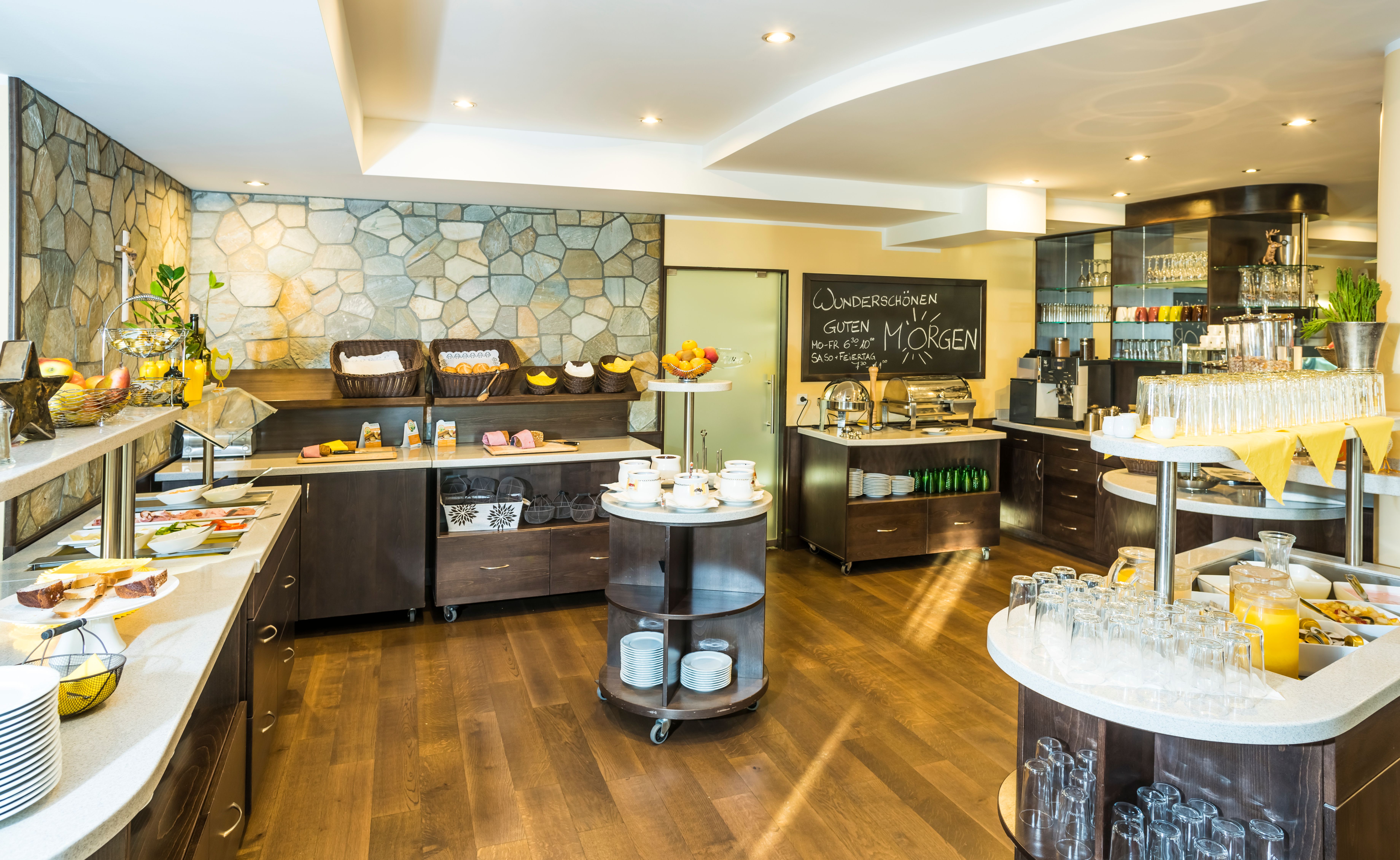 Ein Frühstücksbuffet mit verschiedenen Speisen und Getränken in einem hellen Raum.