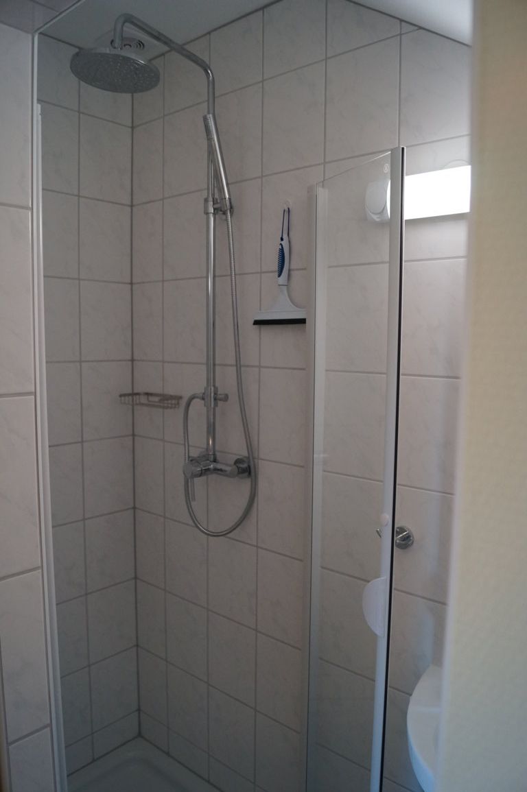 Eine moderne Duschkabine mit Fliesen, Duschkopf und Glaswand.